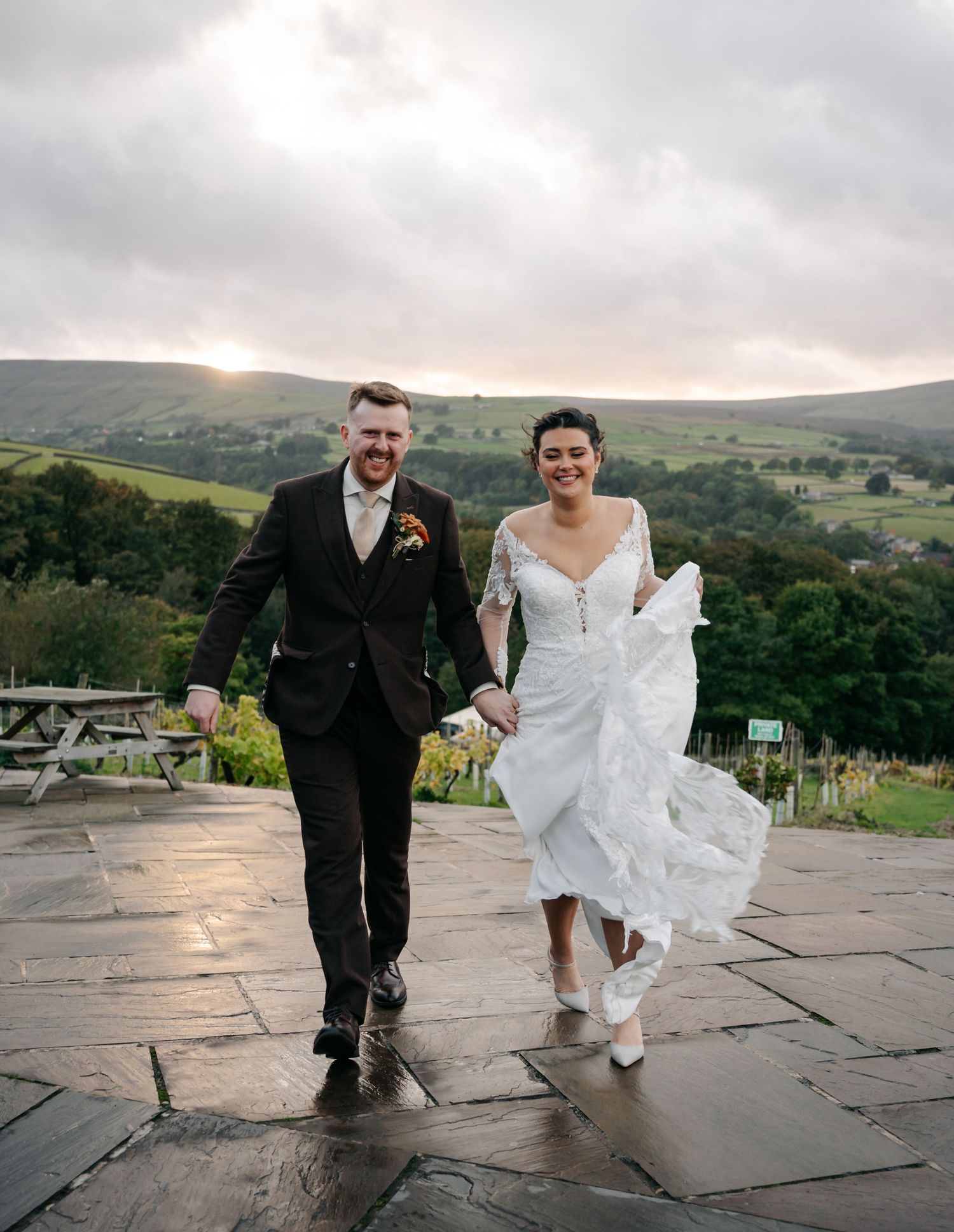 Couple walking together on stone patio with scenic mountain landscape in background.