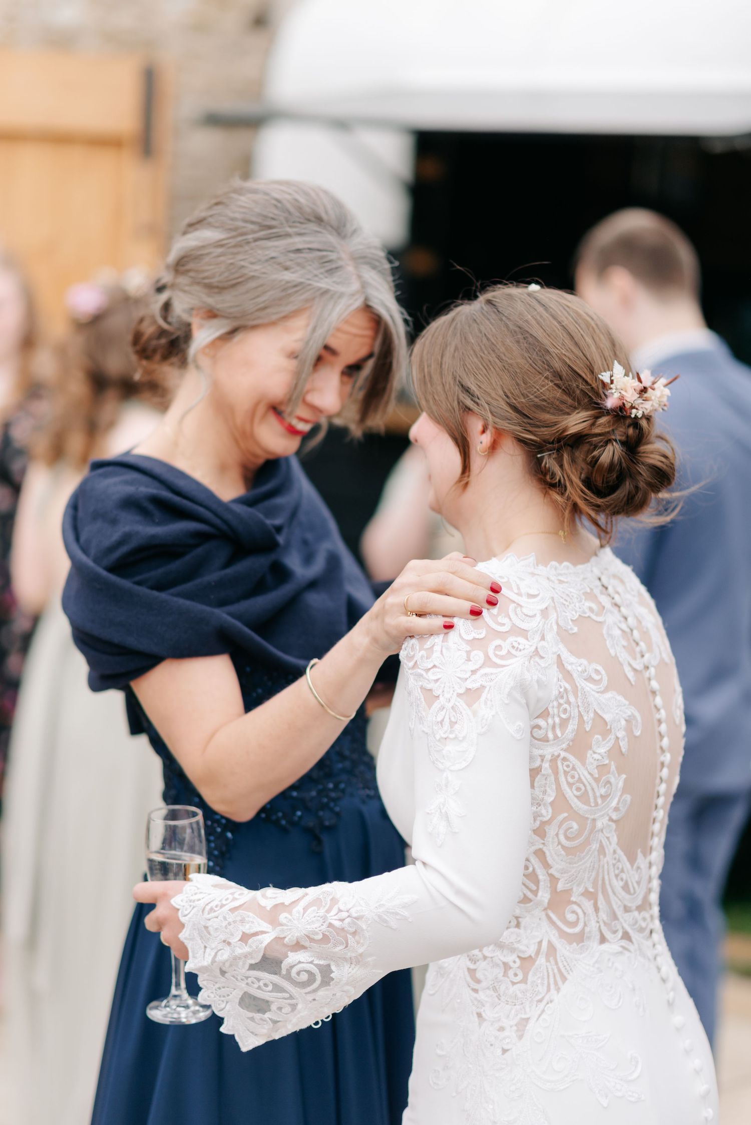 Wedding guests in navy dresses embrace during celebration.