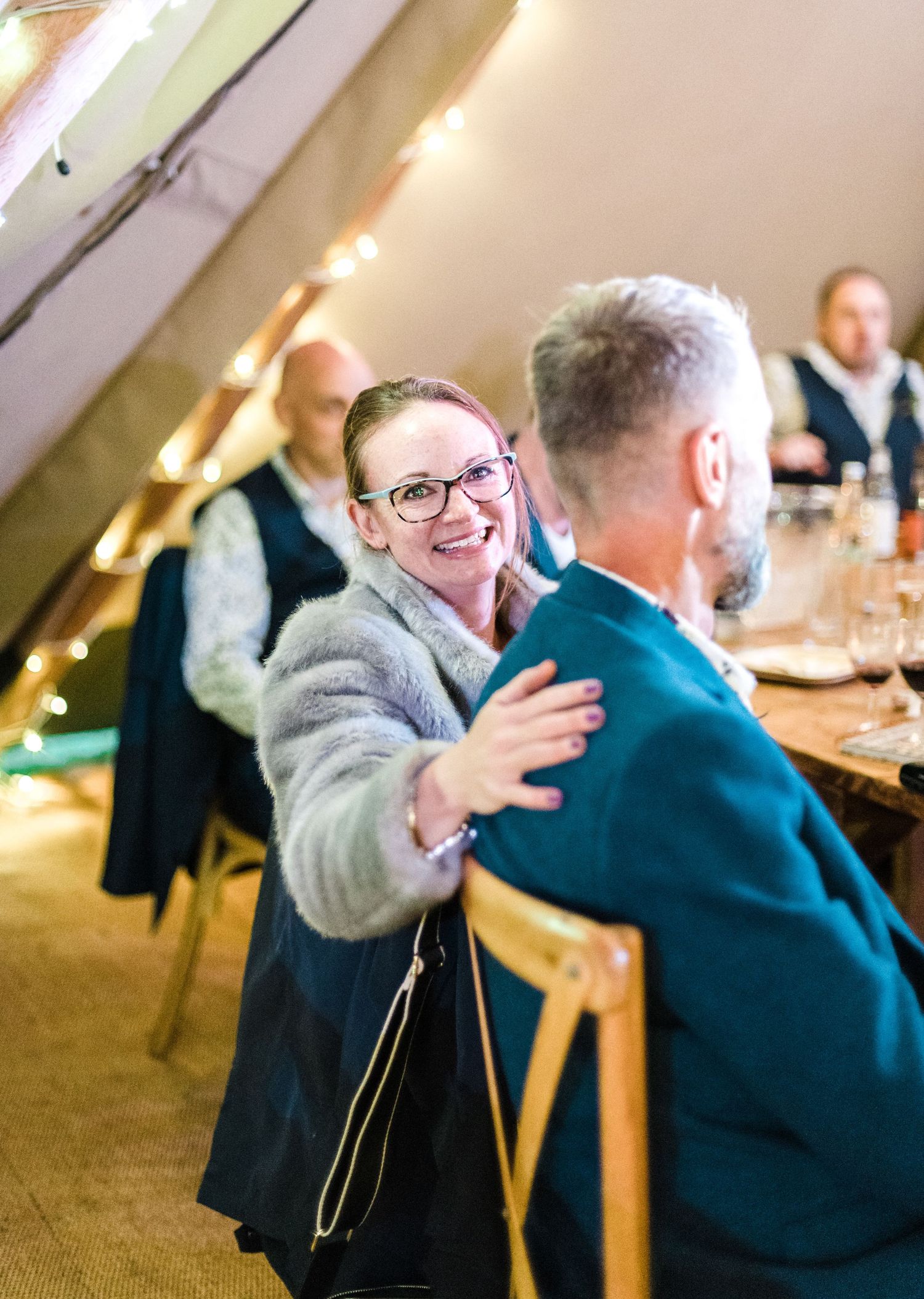Guests sharing a warm moment during a reception under tent lighting.