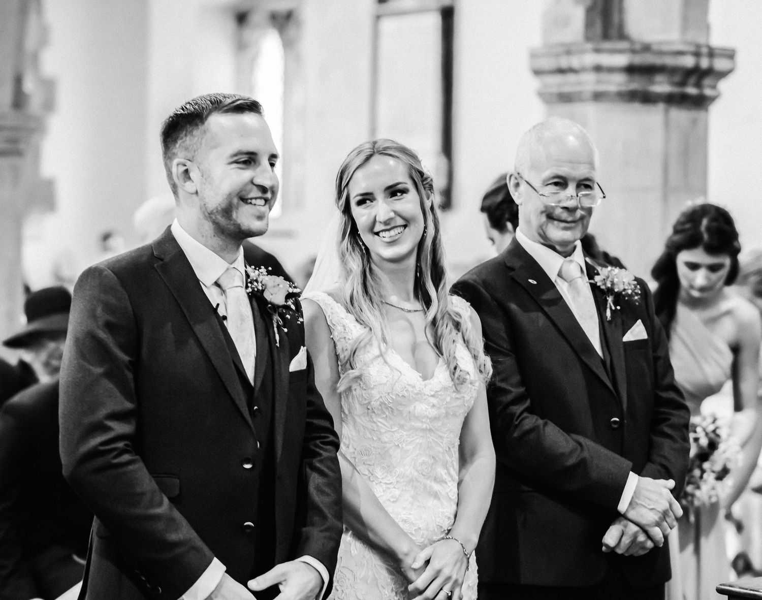 Black and white candid moment during church wedding ceremony with joyful expressions.