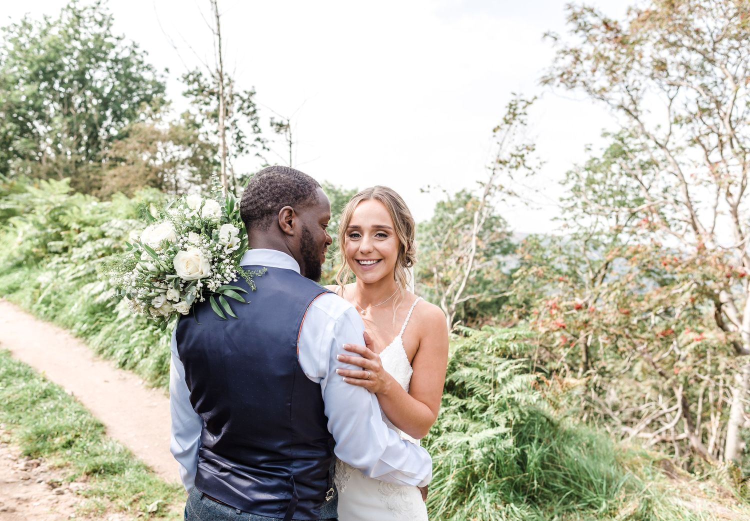A couple shares an intimate moment on their wedding day surrounded by greenery.