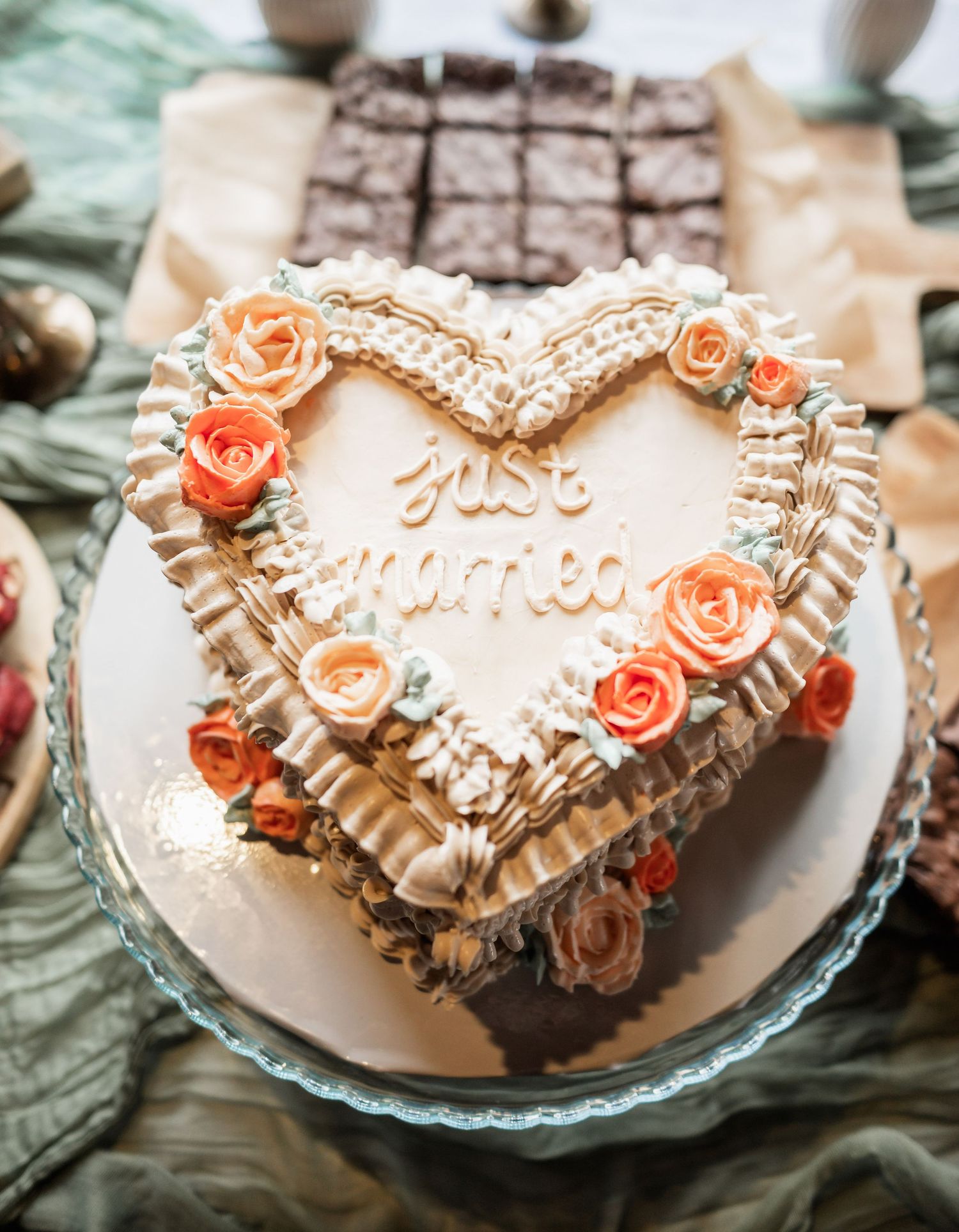 Heart-shaped wedding cake decorated with peach roses and white frosting.