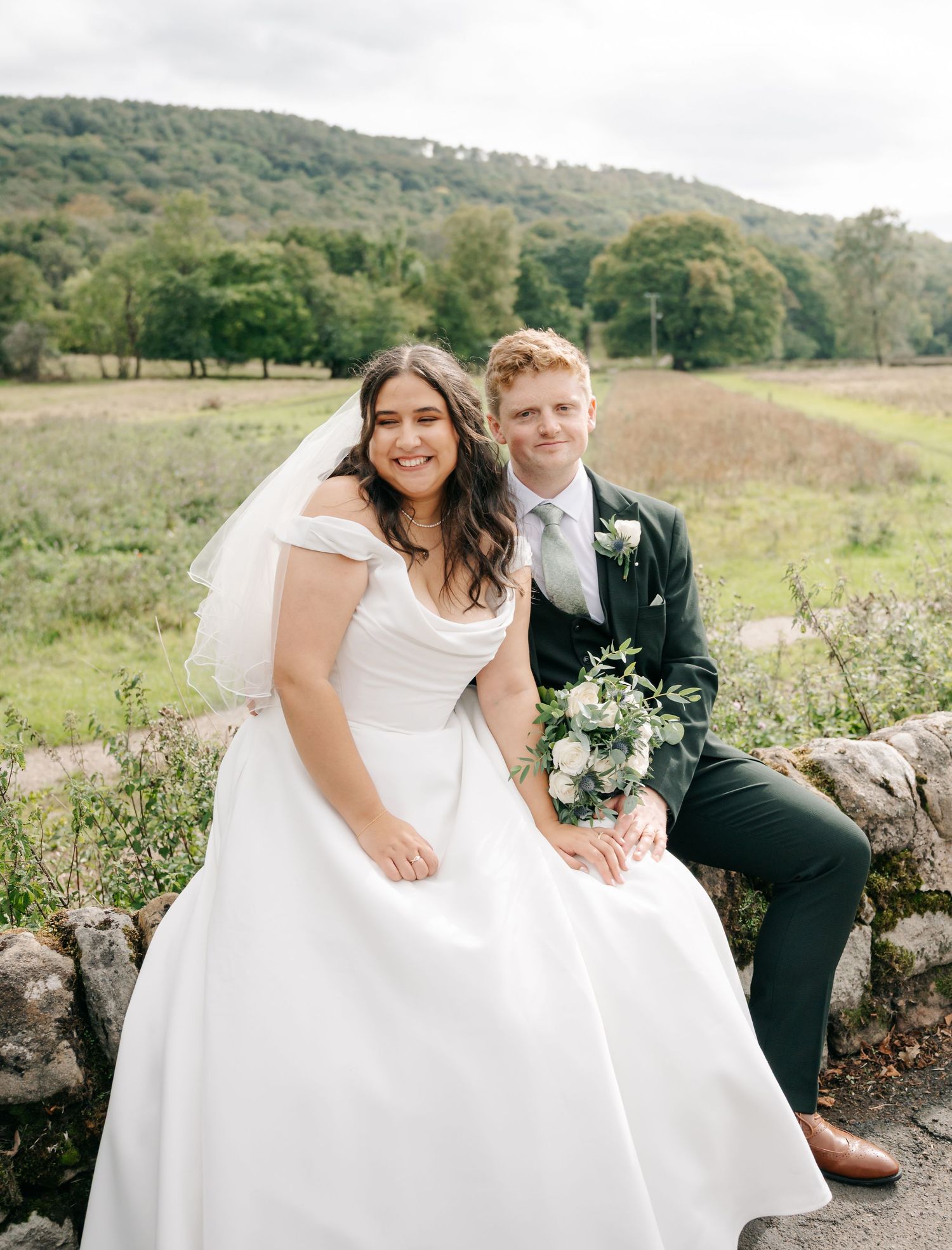 A romantic wedding photoshoot on a hillside featuring a flowing white dress against a natural landscape.