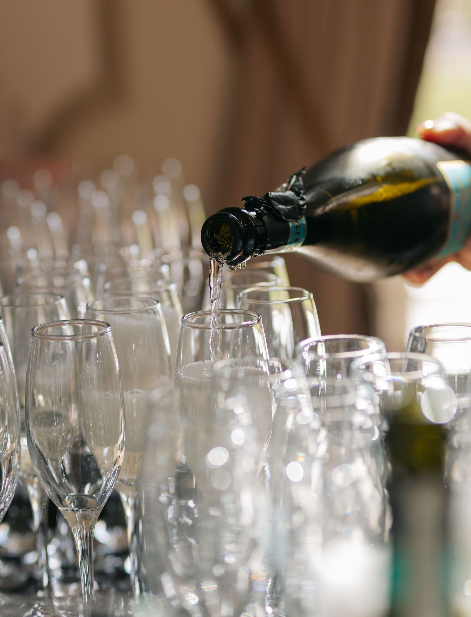Wine glasses lined up at a wedding reception bar service area.