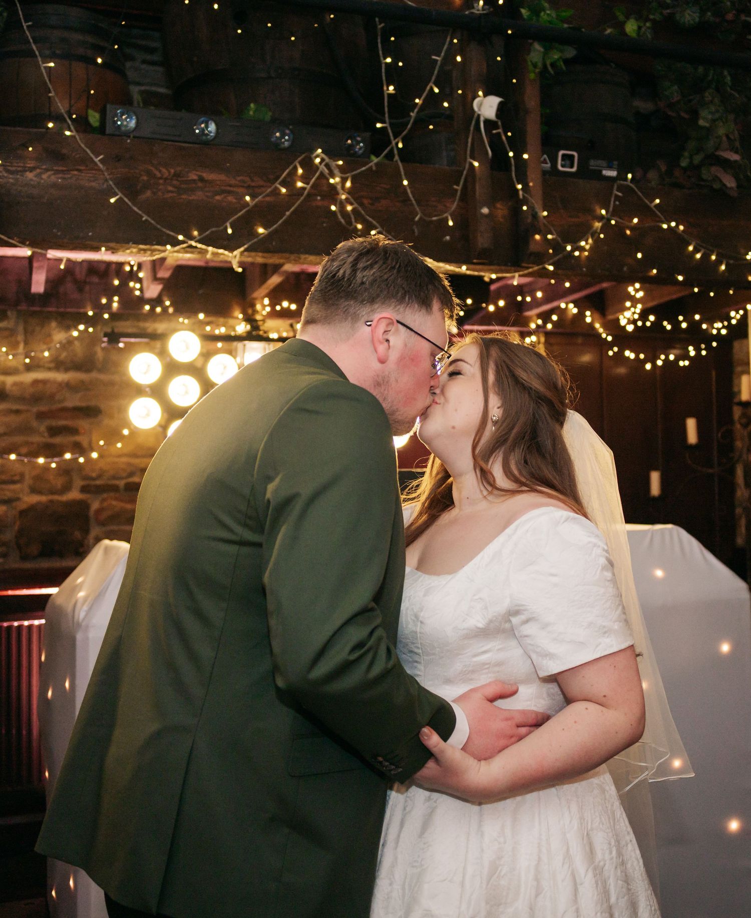 Romantic first dance between newlyweds under twinkling lights at their reception.