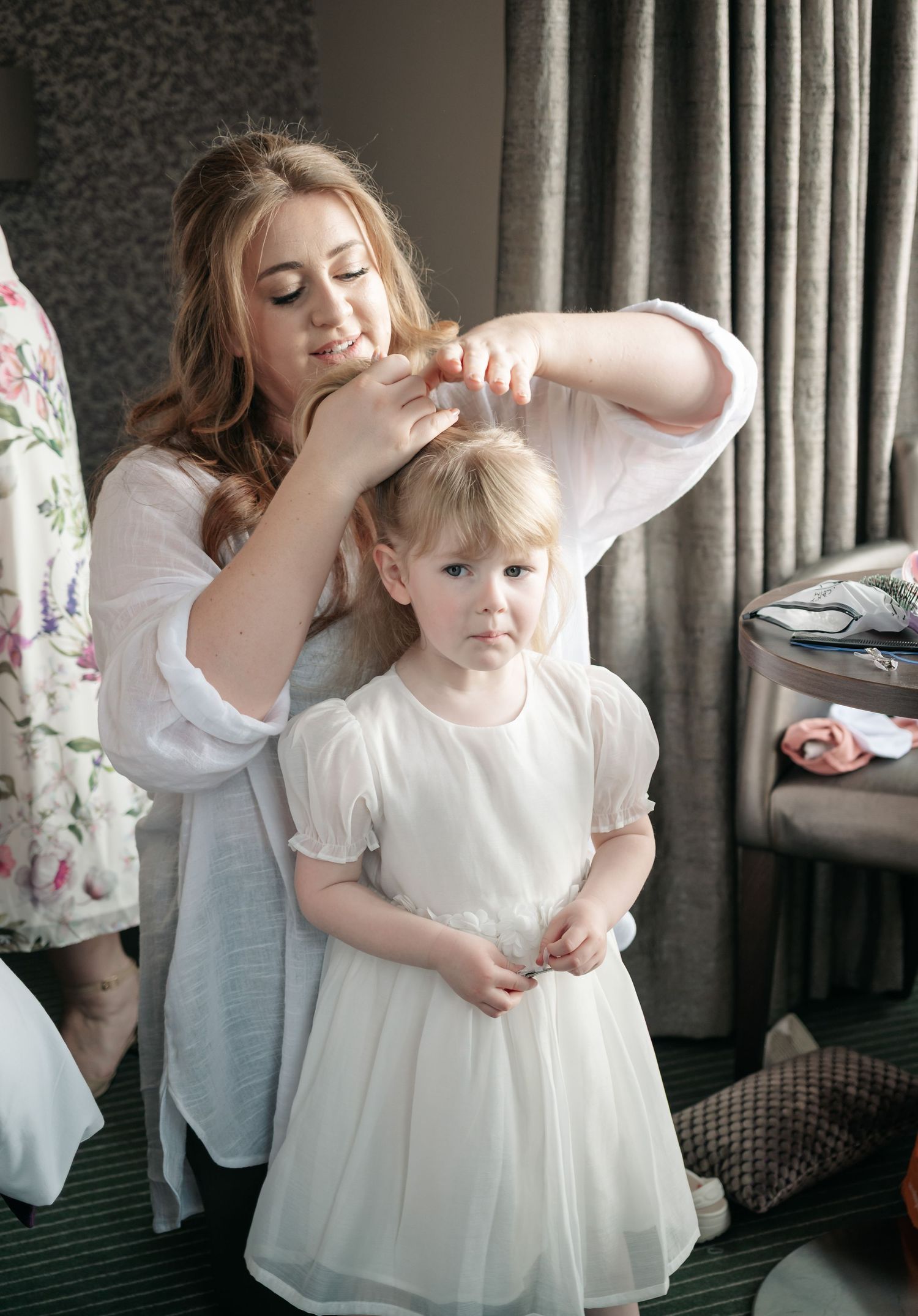 A tender moment captured in a series of photos showing a white dress being adjusted in an elegant interior setting.