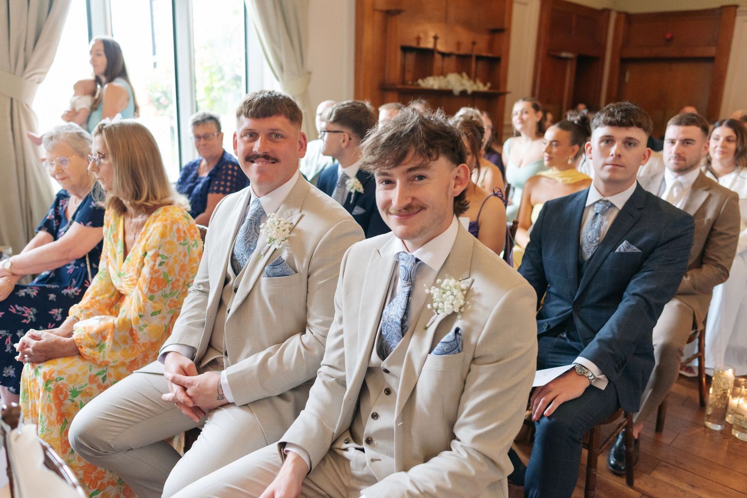 Wedding ceremony guests seated in rows wearing light colored formal attire.