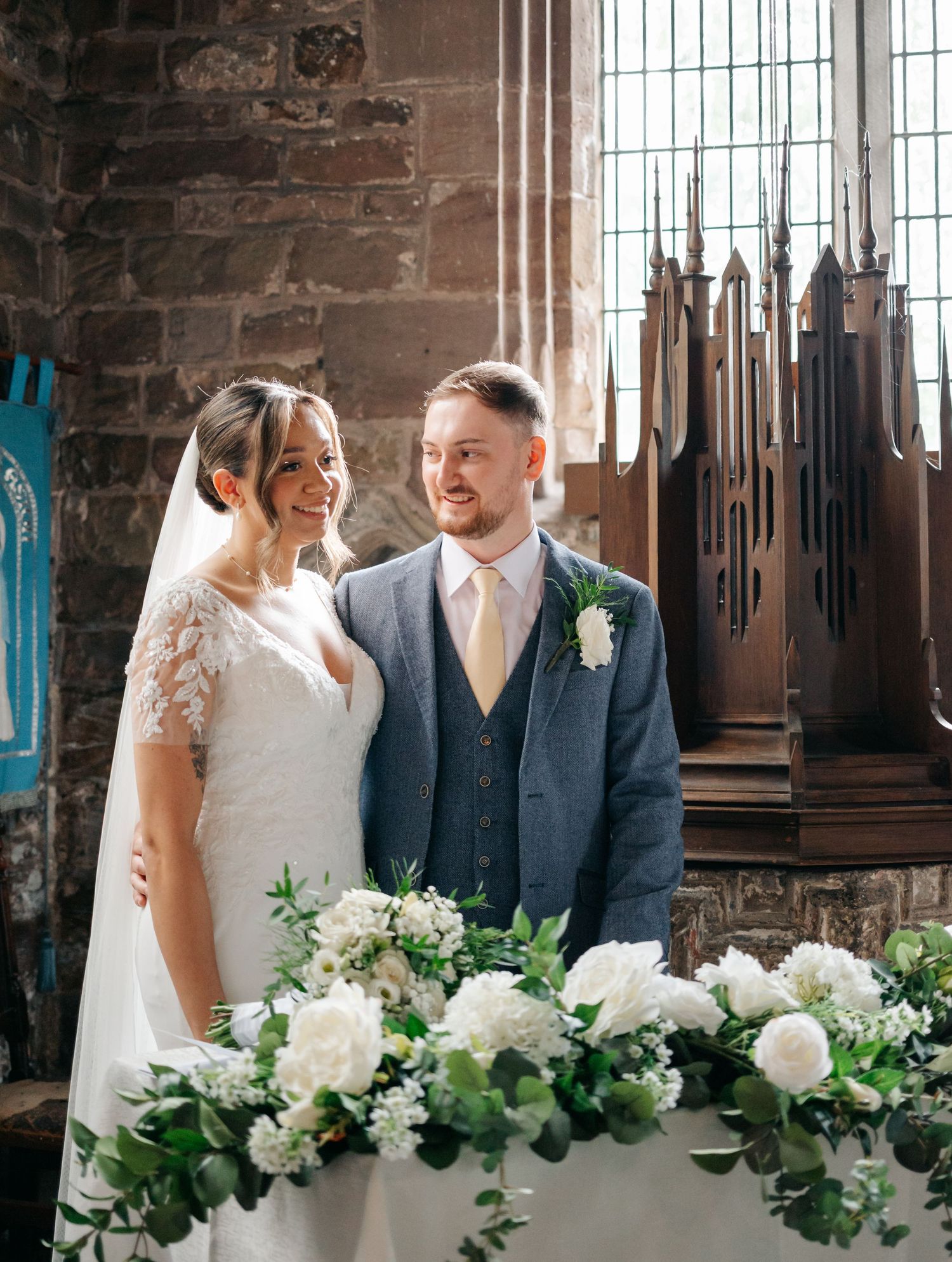 Romantic wedding ceremony setup with white floral arrangements in a historic stone church.
