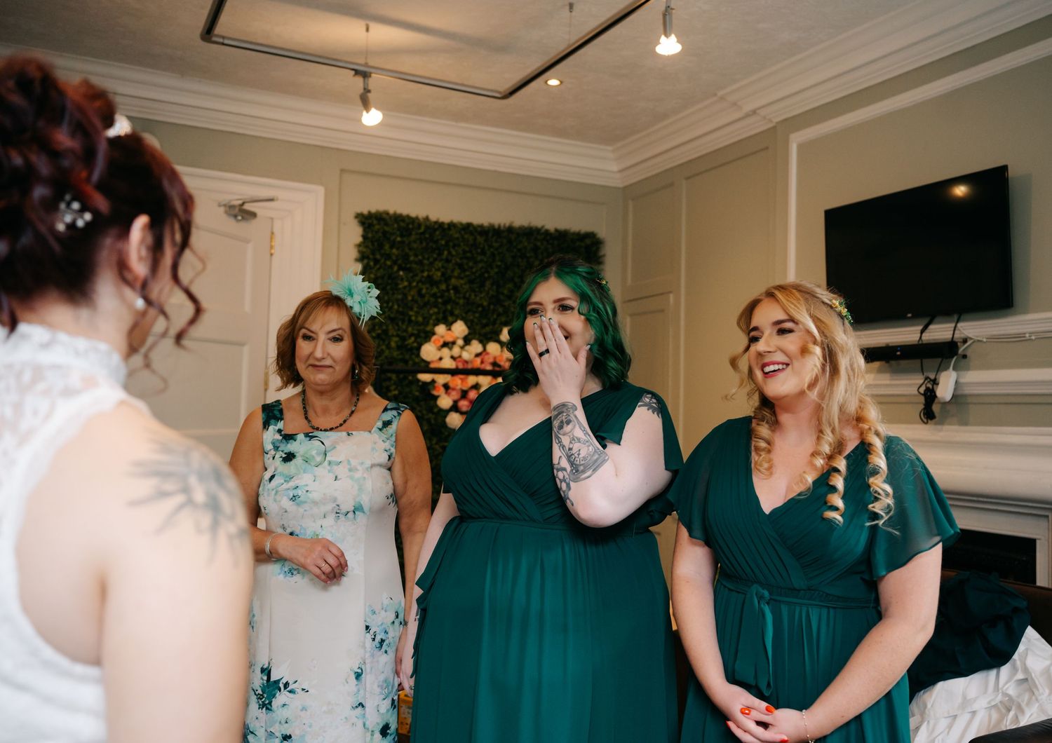 Wedding party members in teal dresses sharing laughter during preparation.