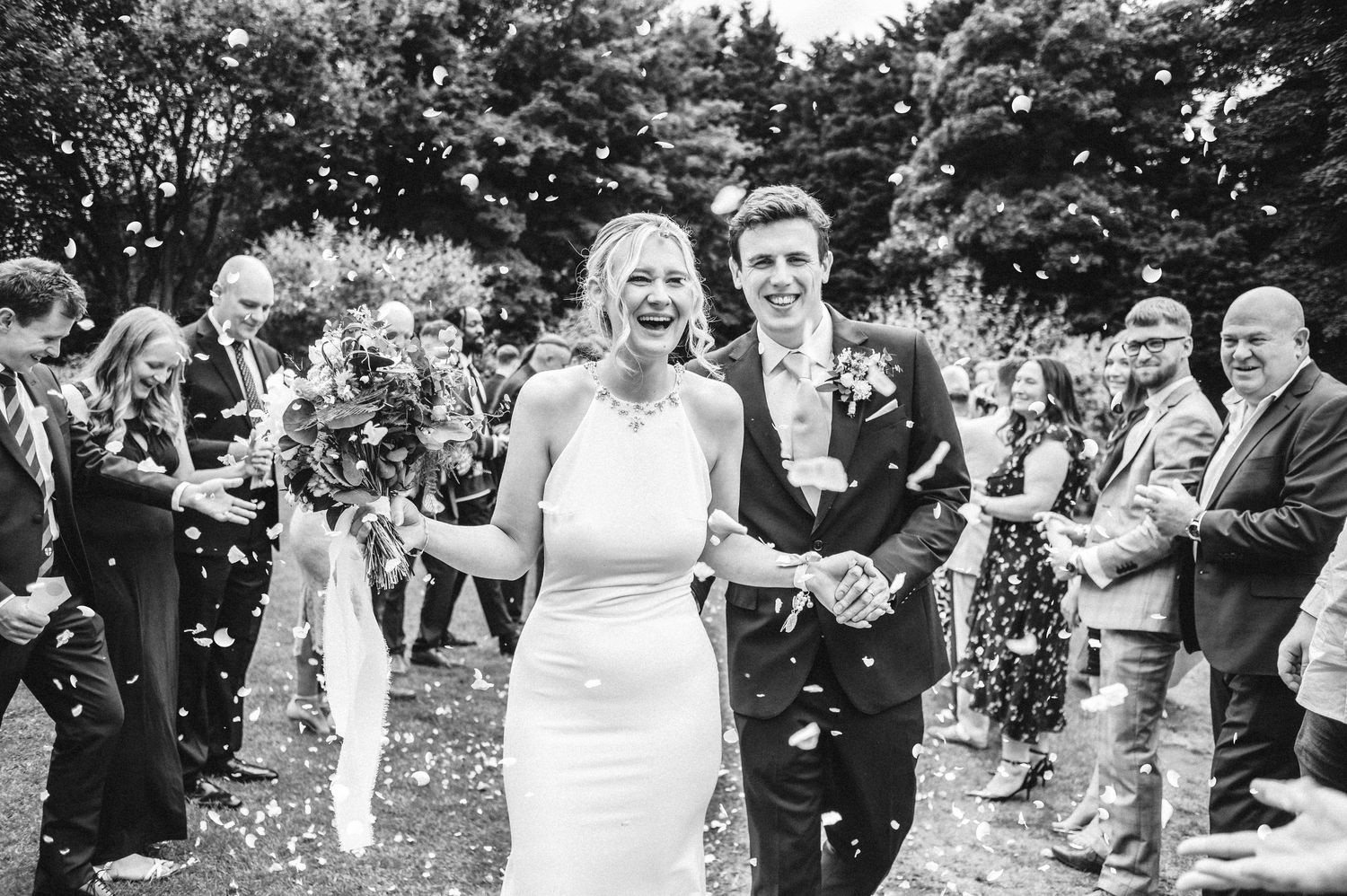 A series of black and white wedding photos showing joyful moments between couples and guests at an outdoor celebration.