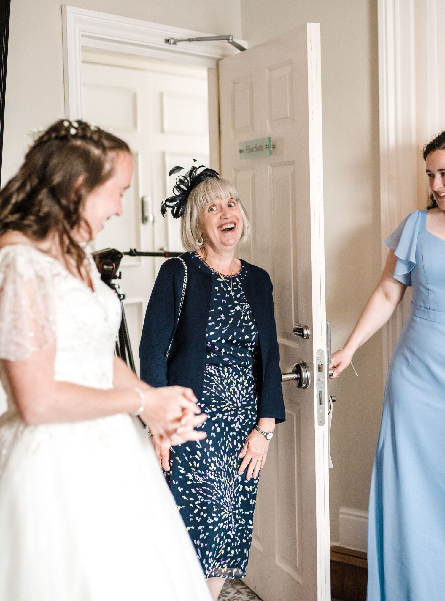 Joyful moment shared between wedding party members in a bright hallway.