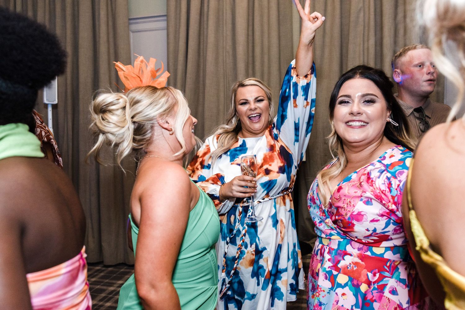 Wedding guests in colorful attire dancing and celebrating on dance floor.