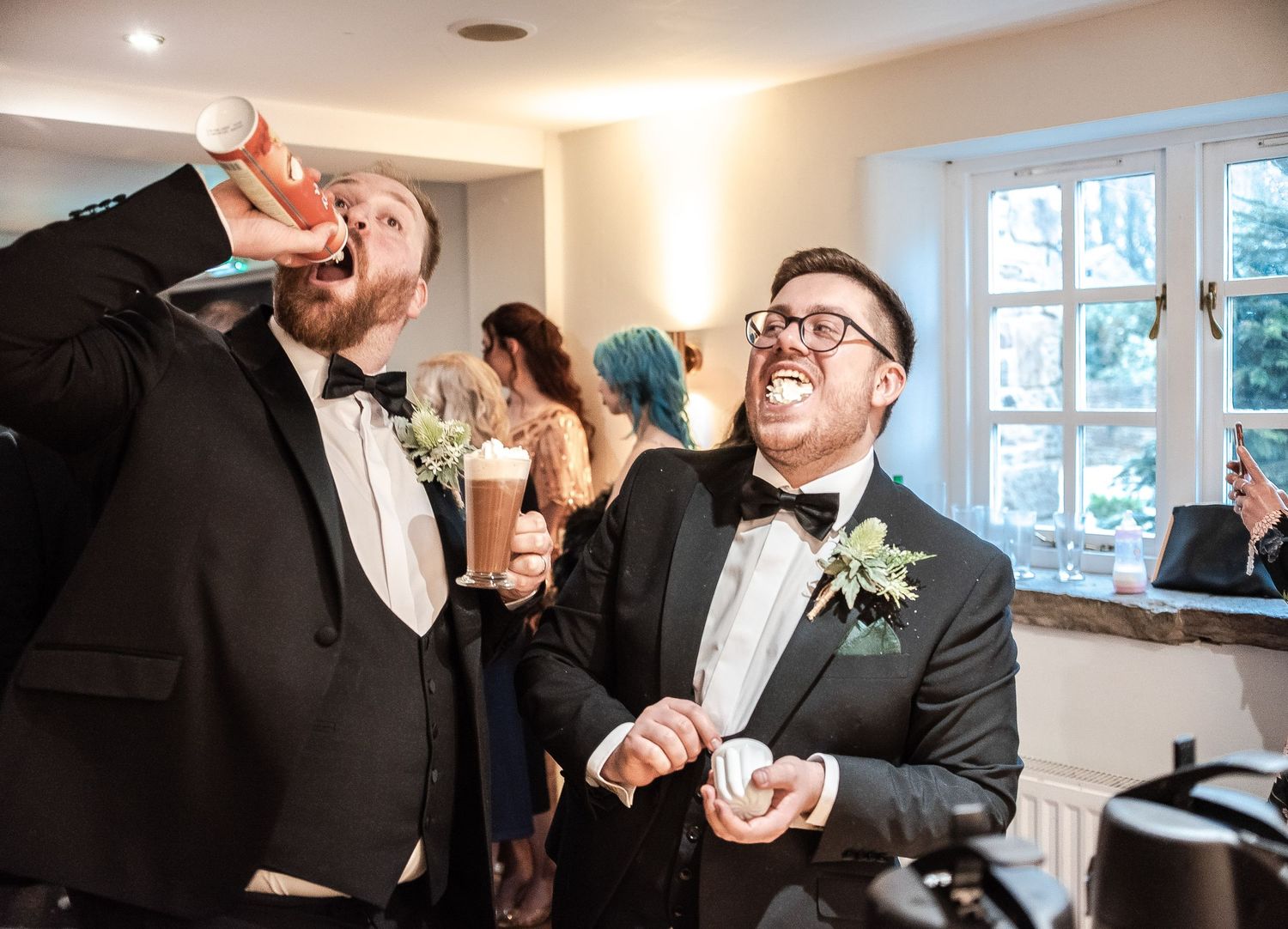 Wedding reception celebration with guests laughing and enjoying drinks in a bright indoor setting.