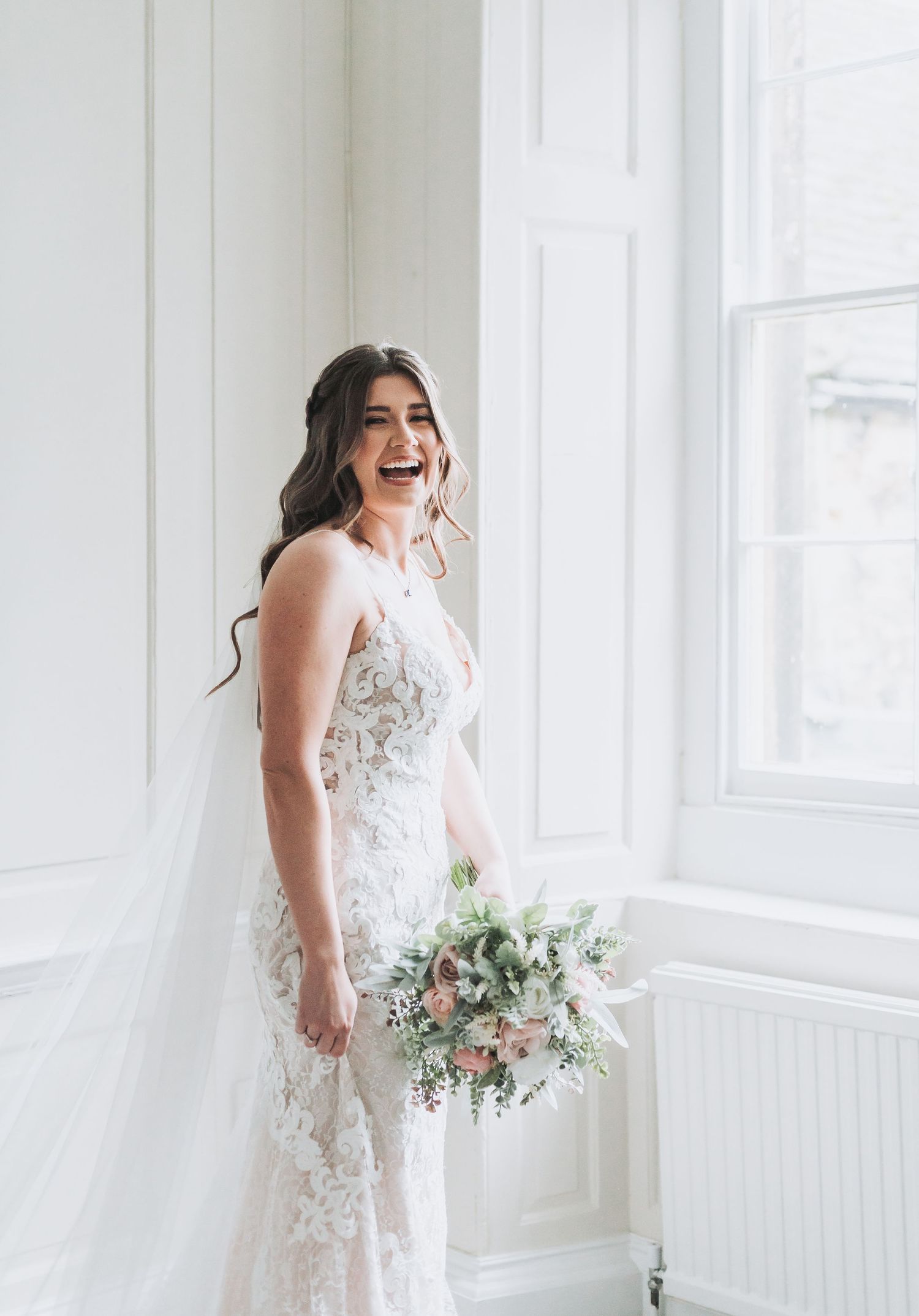 A joyful moment captured in a bright white room with someone holding a wedding bouquet.