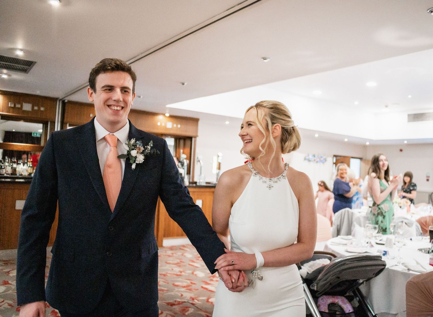 A joyful exchange during wedding speeches at an elegant reception with white decor and floral centerpieces.