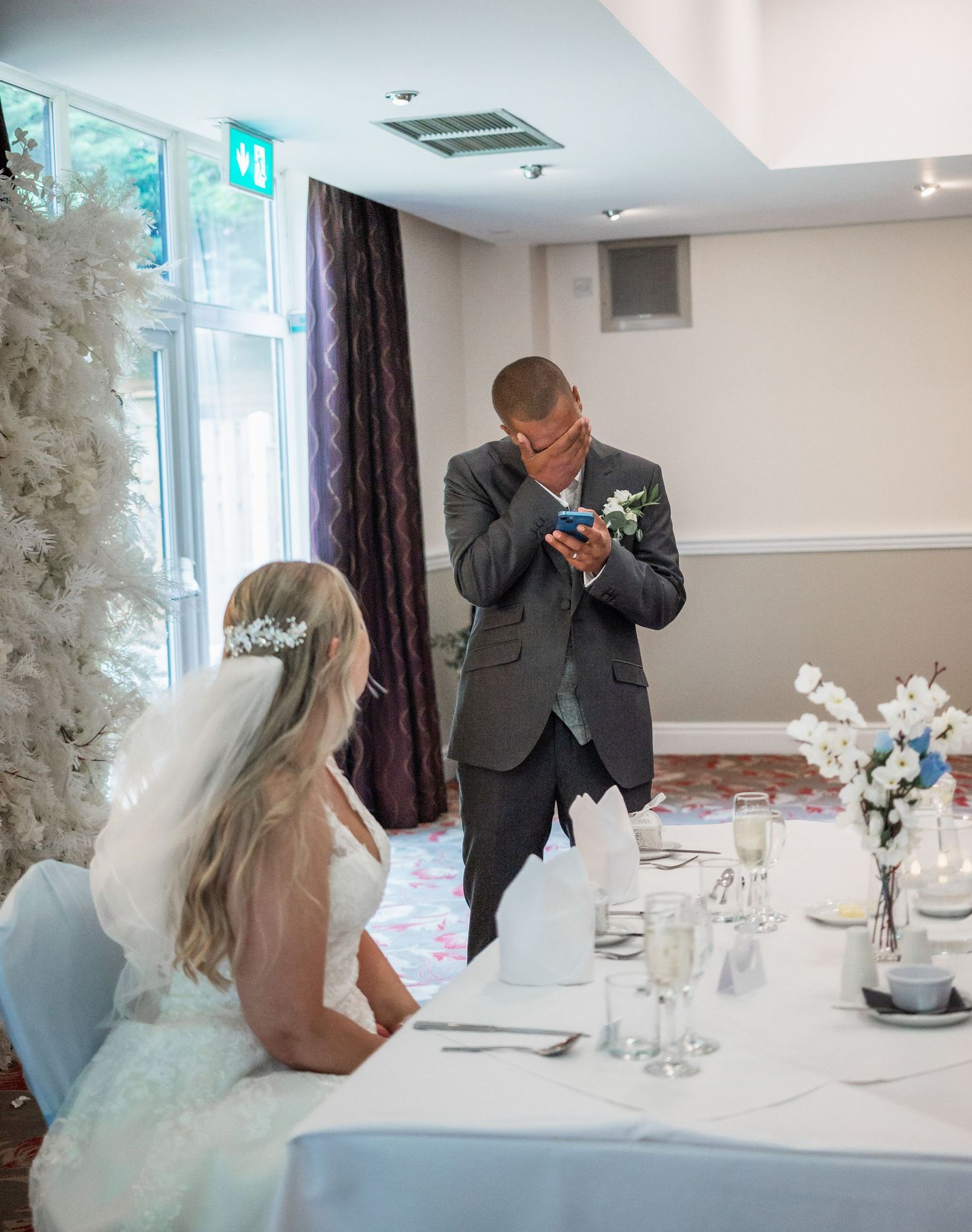 An emotional moment during wedding speeches at an elegantly set reception table.
