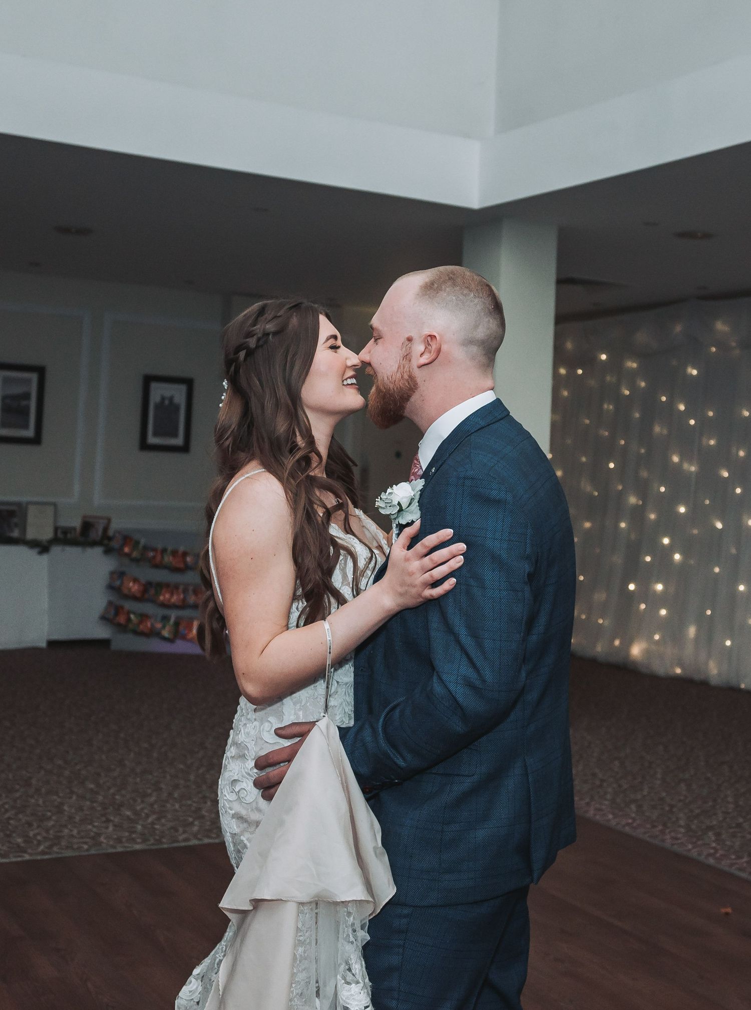 A couple shares an intimate dance moment under twinkling lights.