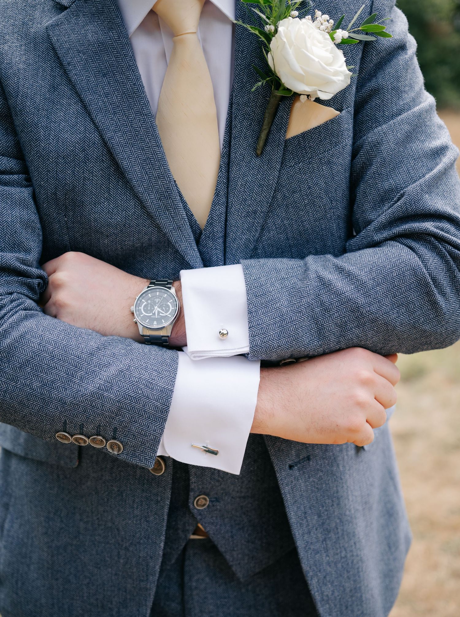 Close-up details of gray suit jackets with decorative cufflinks and white dress shirts.