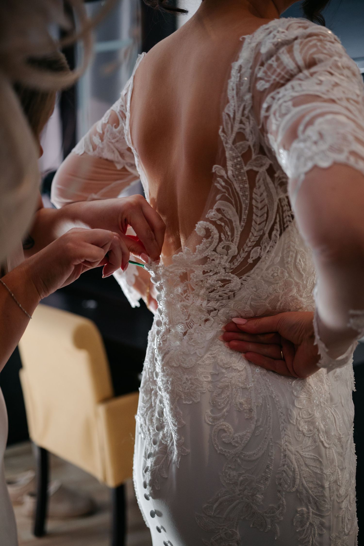 Close-up details of an intricate lace wedding dress being adjusted.