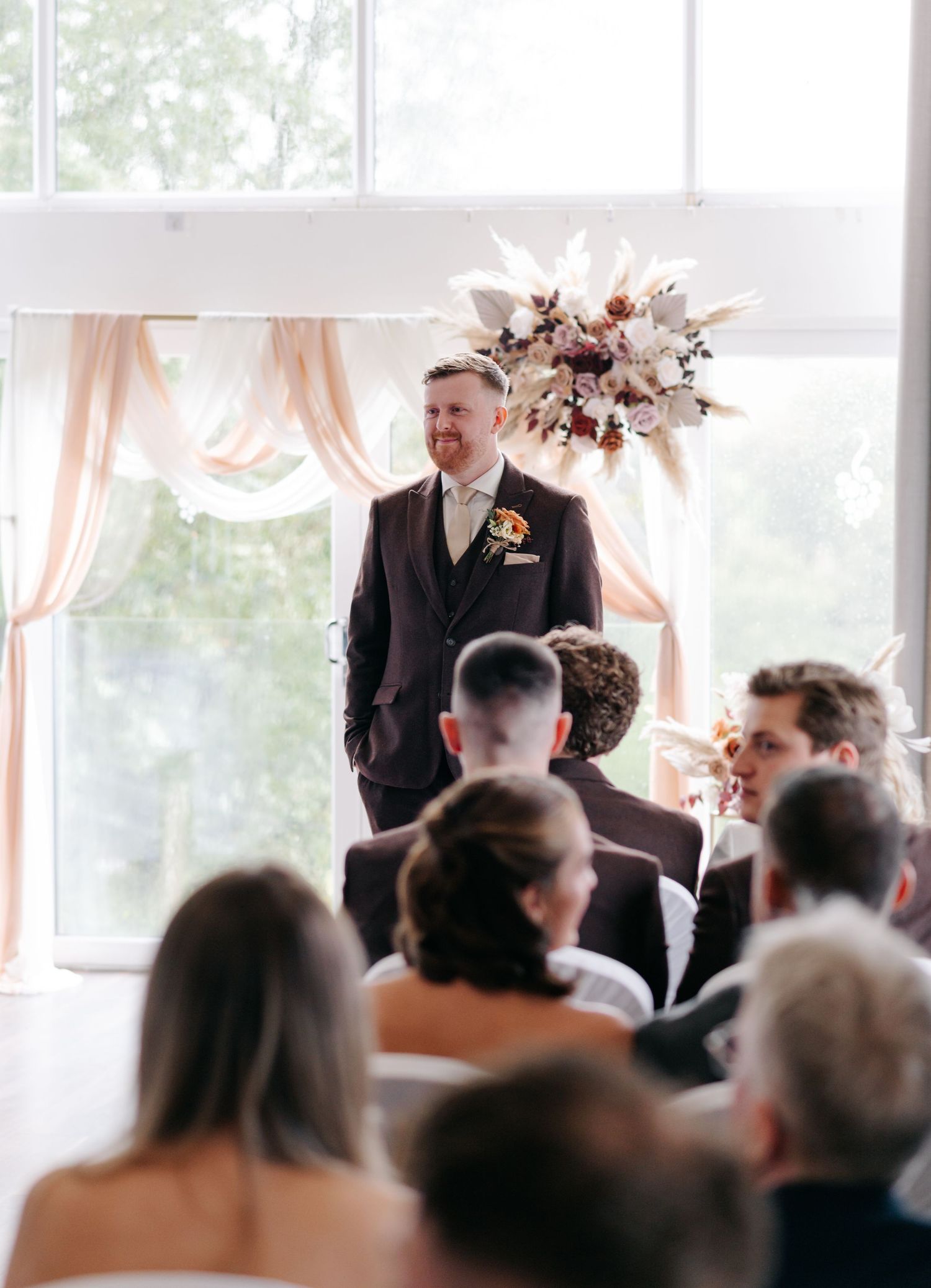 Wedding ceremony venue with guests seated and decorated with soft peach drapes and floral arrangements.