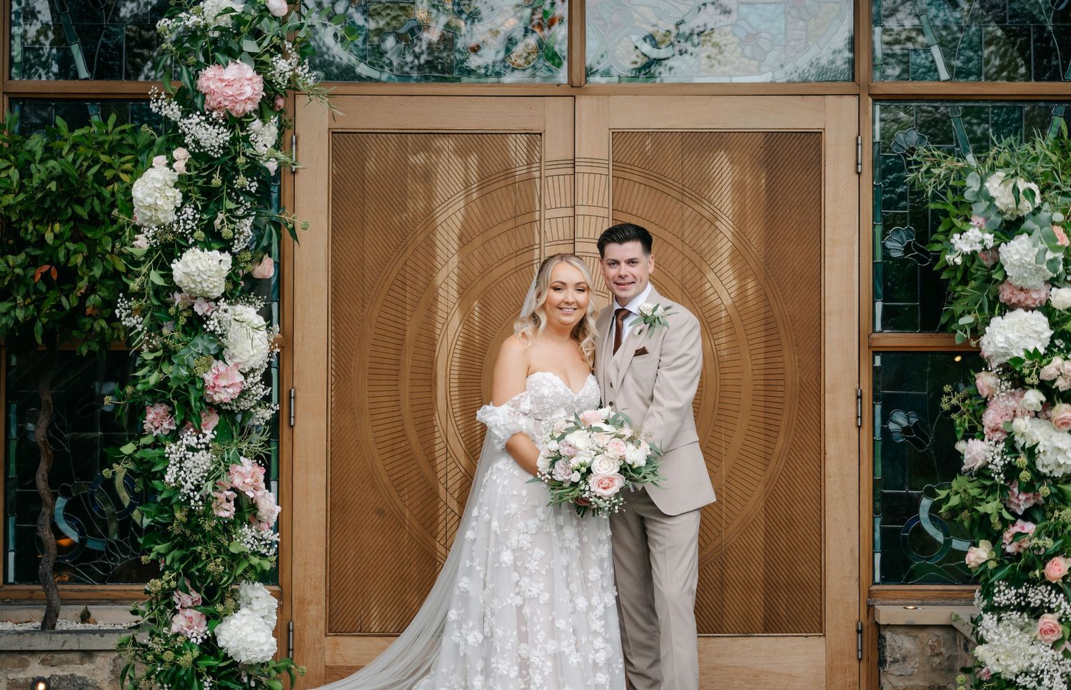 Outdoor wedding ceremony setup with white floral arrangements and wooden decor.