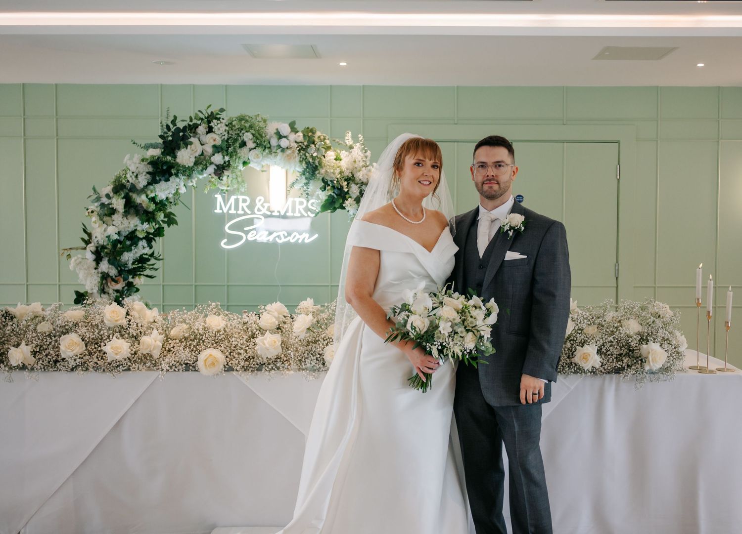 An elegant wedding reception setup with white floral arrangements and decor.