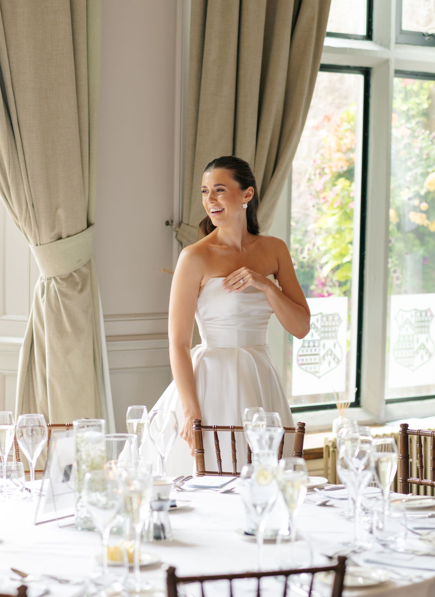 An elegant reception table is set with glassware and place settings in a bright dining room.