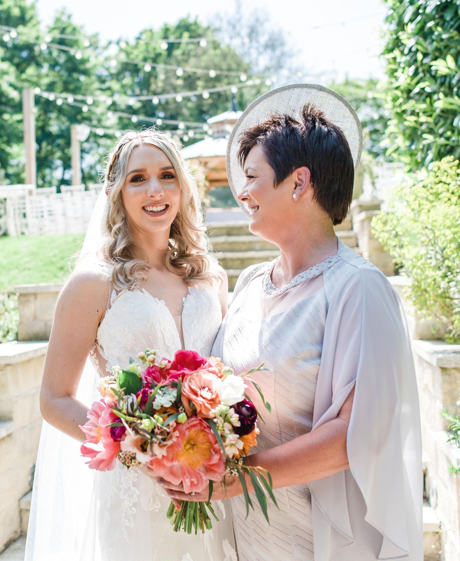 Two people holding vibrant pink and coral bouquets while sharing a joyful moment outdoors.