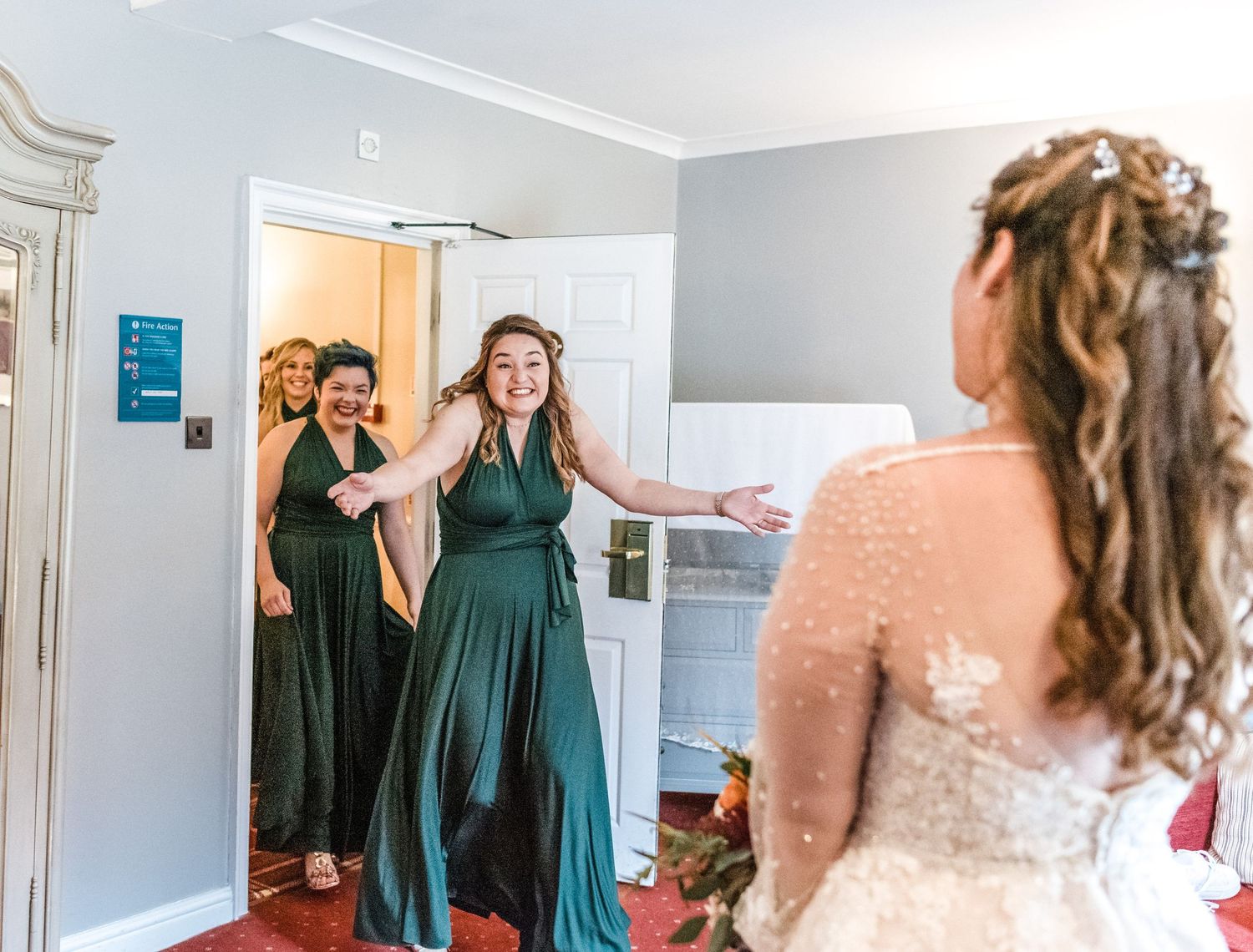 Emotional first look reaction between bridesmaids and bride in preparation room.