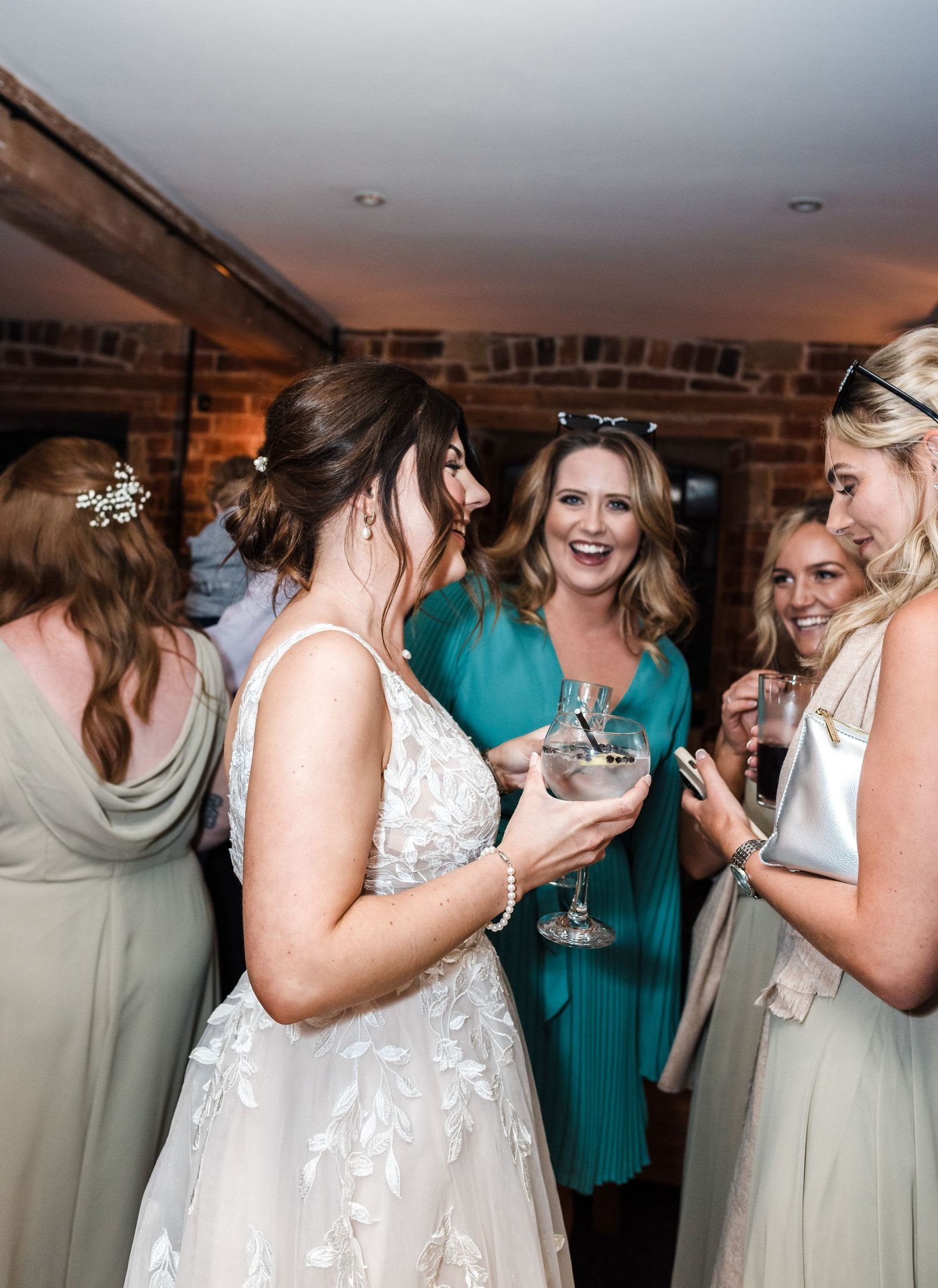Wedding party members sharing laughs and drinks during reception celebration.