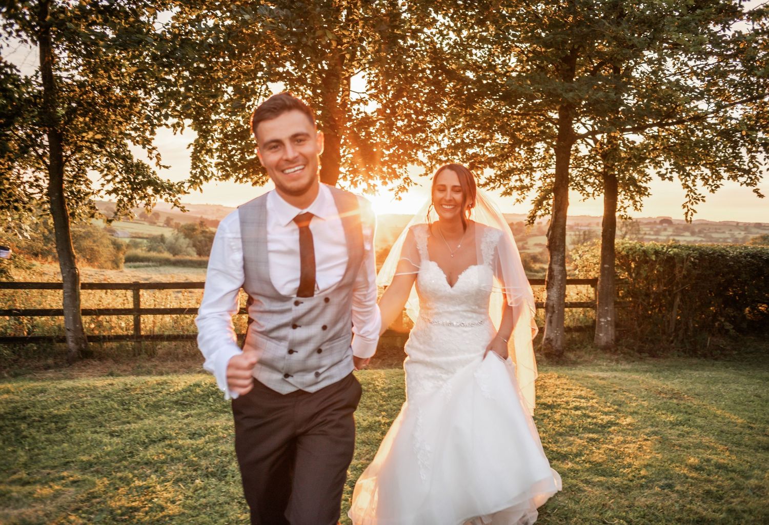Couple running playfully through a sunset-lit garden during their wedding photoshoot.