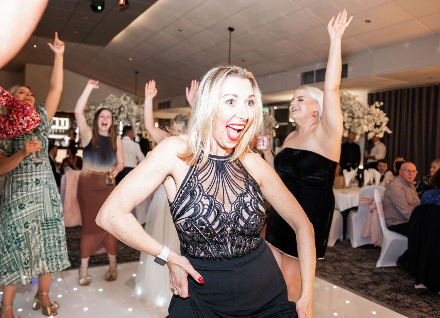 Energetic dancing and celebration at a wedding reception with decorative lighting.