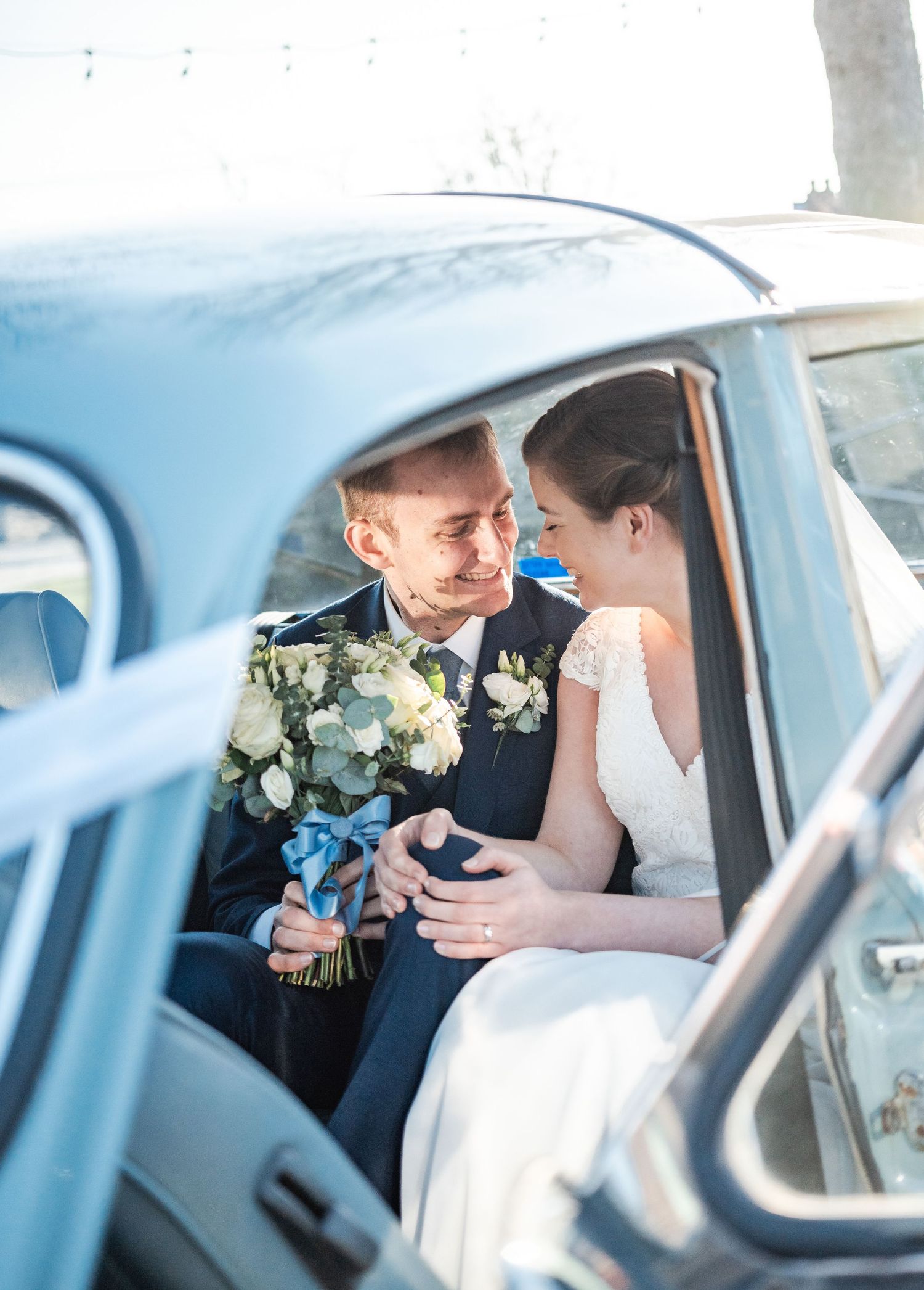 Romantic newlywed couple shares intimate moments inside vintage wedding car.