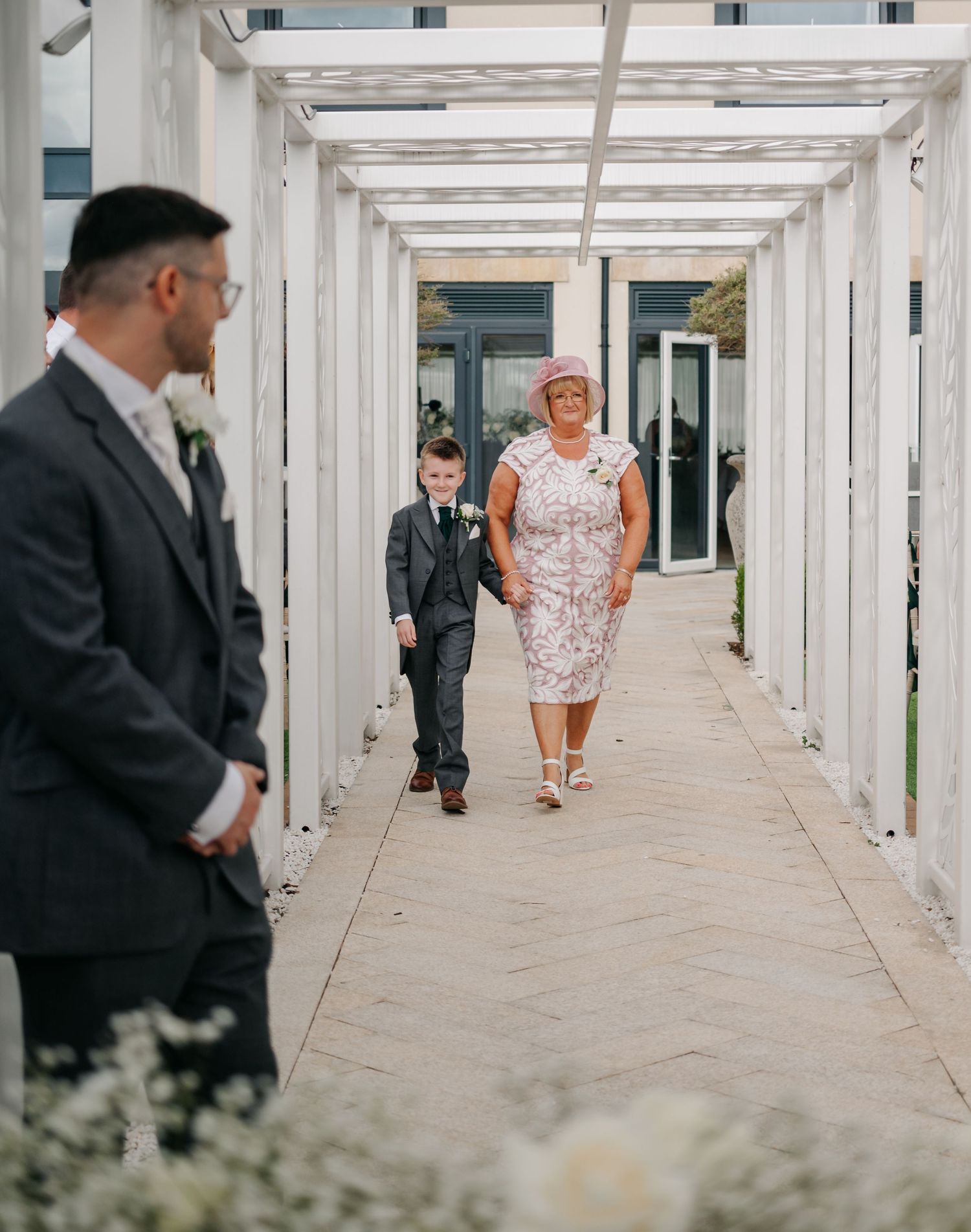 People walking through an elegant white covered walkway with architectural details.