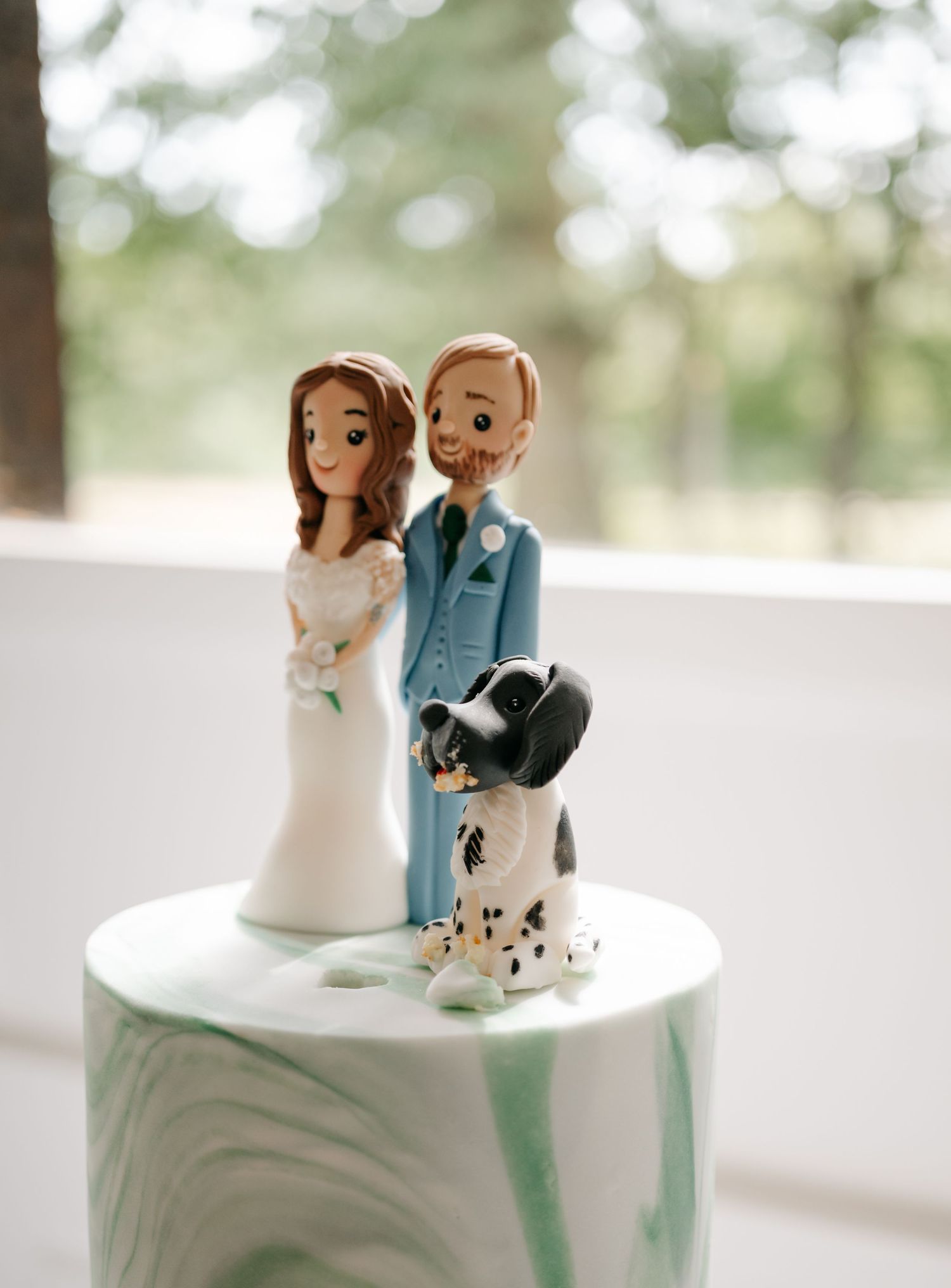 Custom wedding cake topper featuring bride and groom figurines with a small dog.