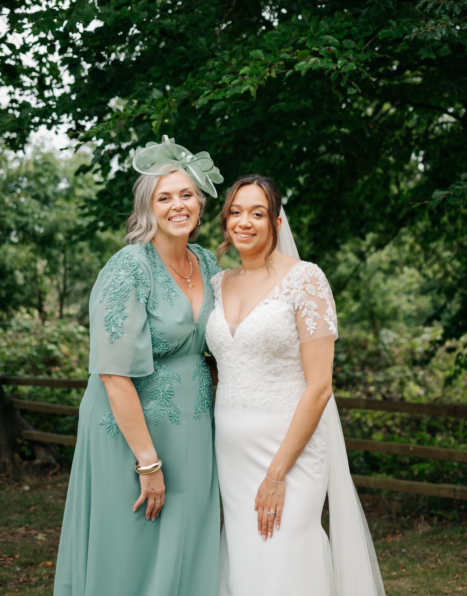 Wedding party members in mint green dresses and white gown pose in garden setting.