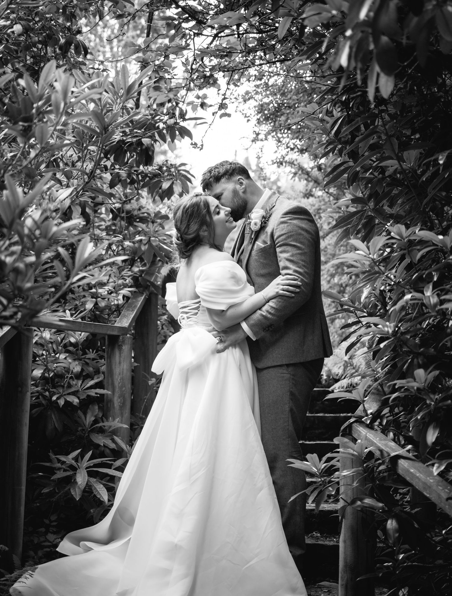 Black and white wedding portraits in a romantic garden setting.