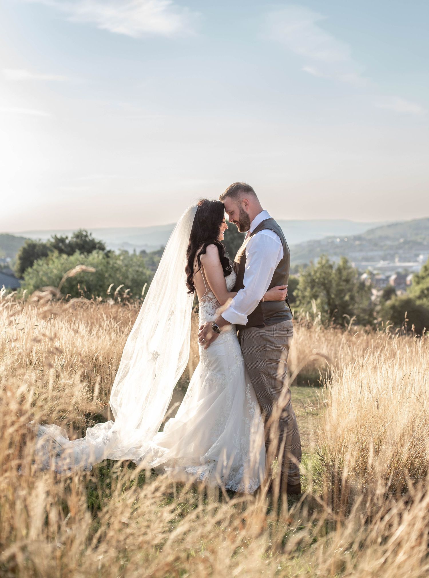 Romantic sunset portrait in tall grass with mountains in background.