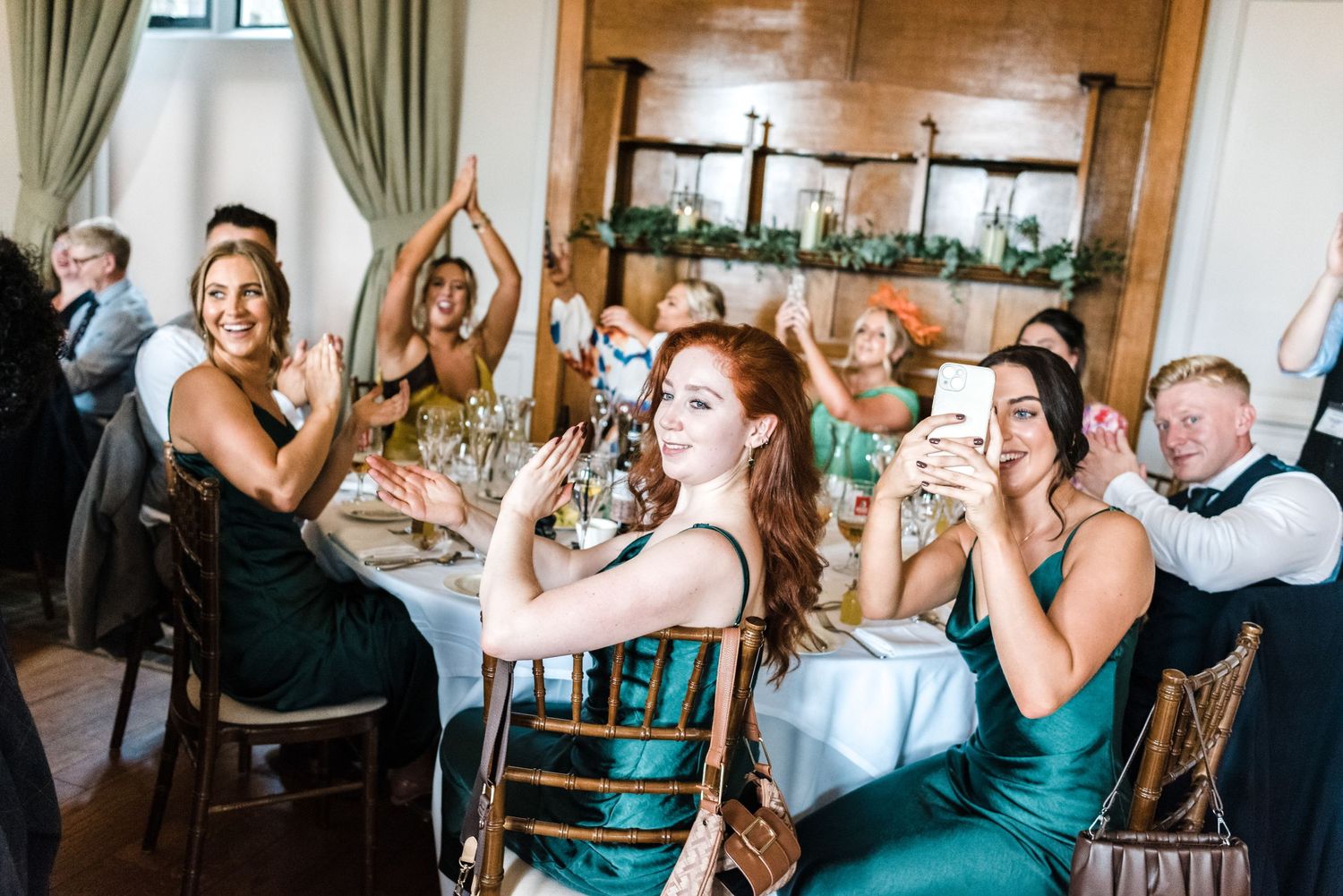 Wedding reception guests in formal attire celebrating at decorated dining tables.