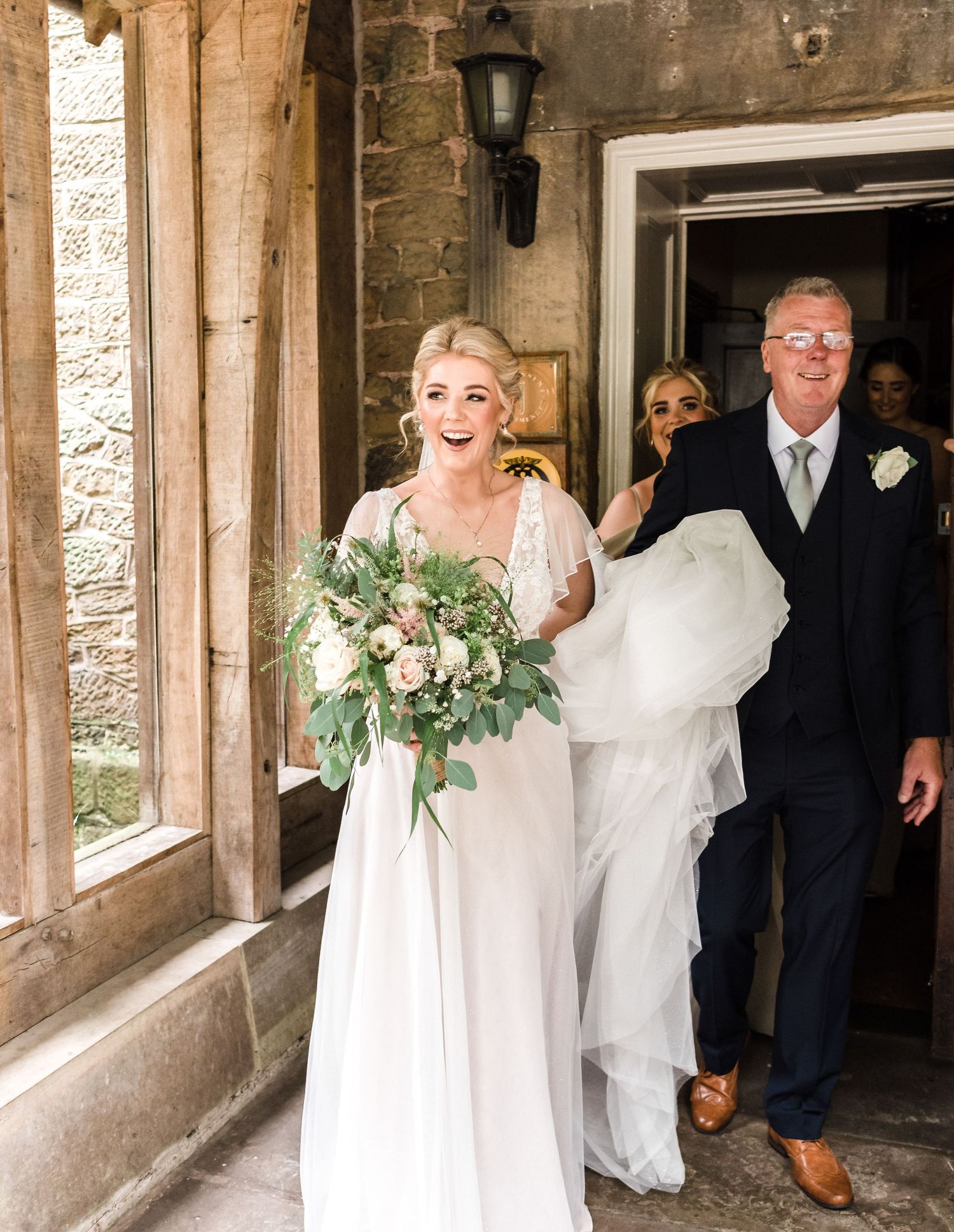 A couple exits through a stone archway entrance after their wedding ceremony.