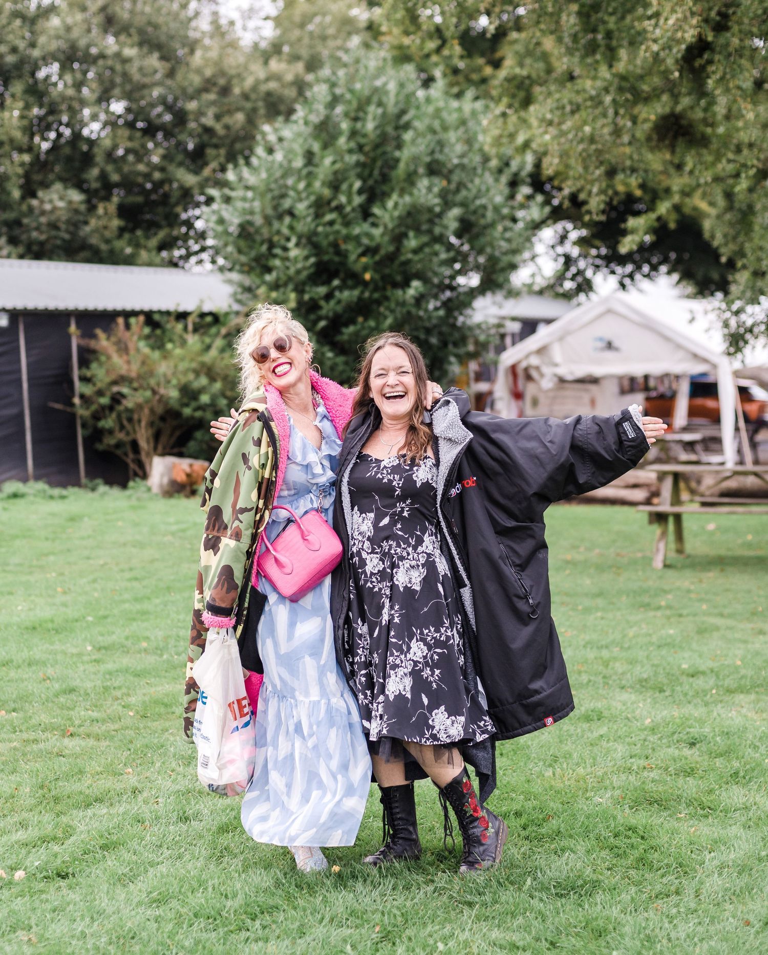 Group of wedding guests posing playfully outdoors on grass.