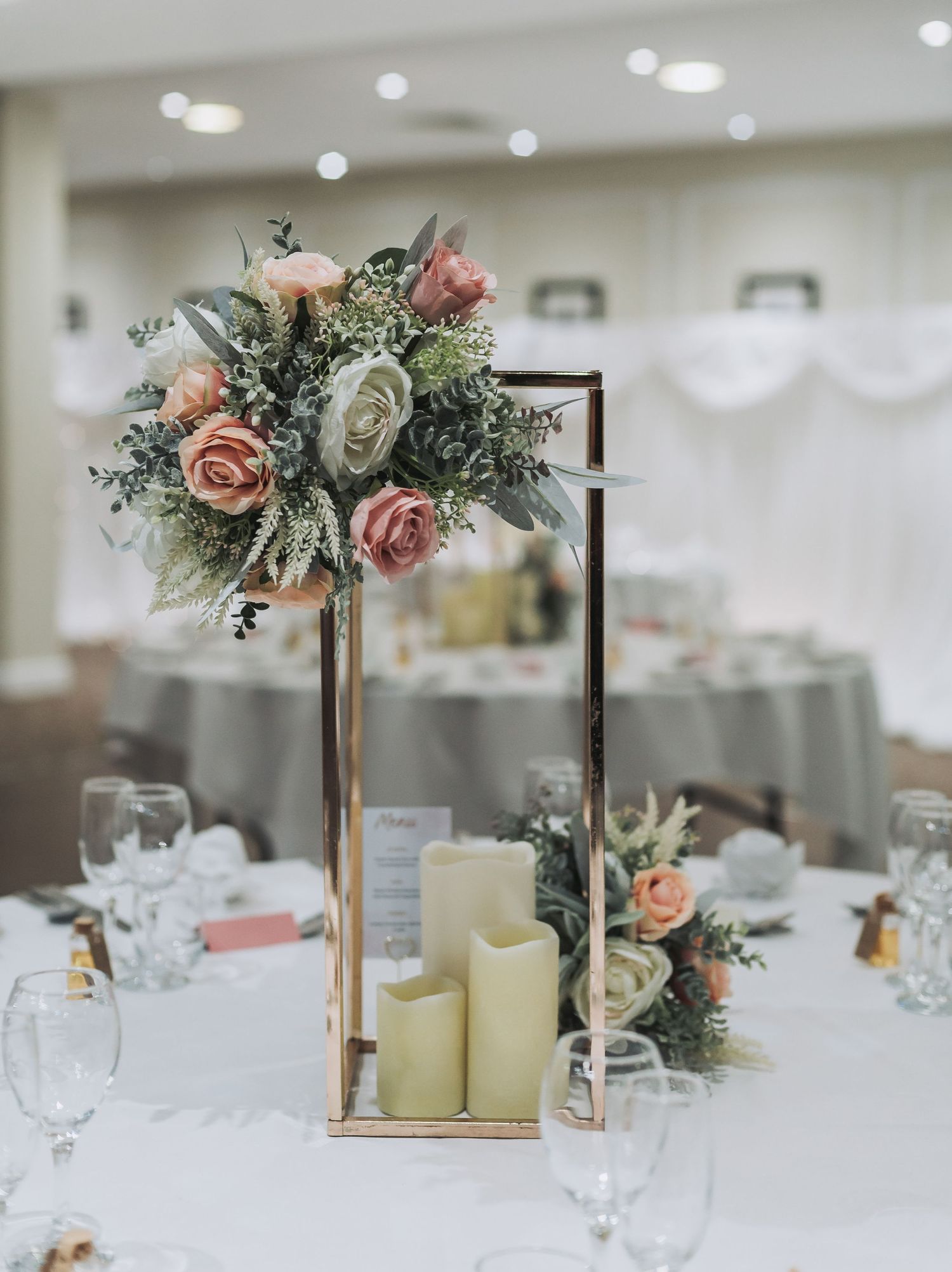Elegant centerpiece with pink and white roses in gold lantern with pillar candles.