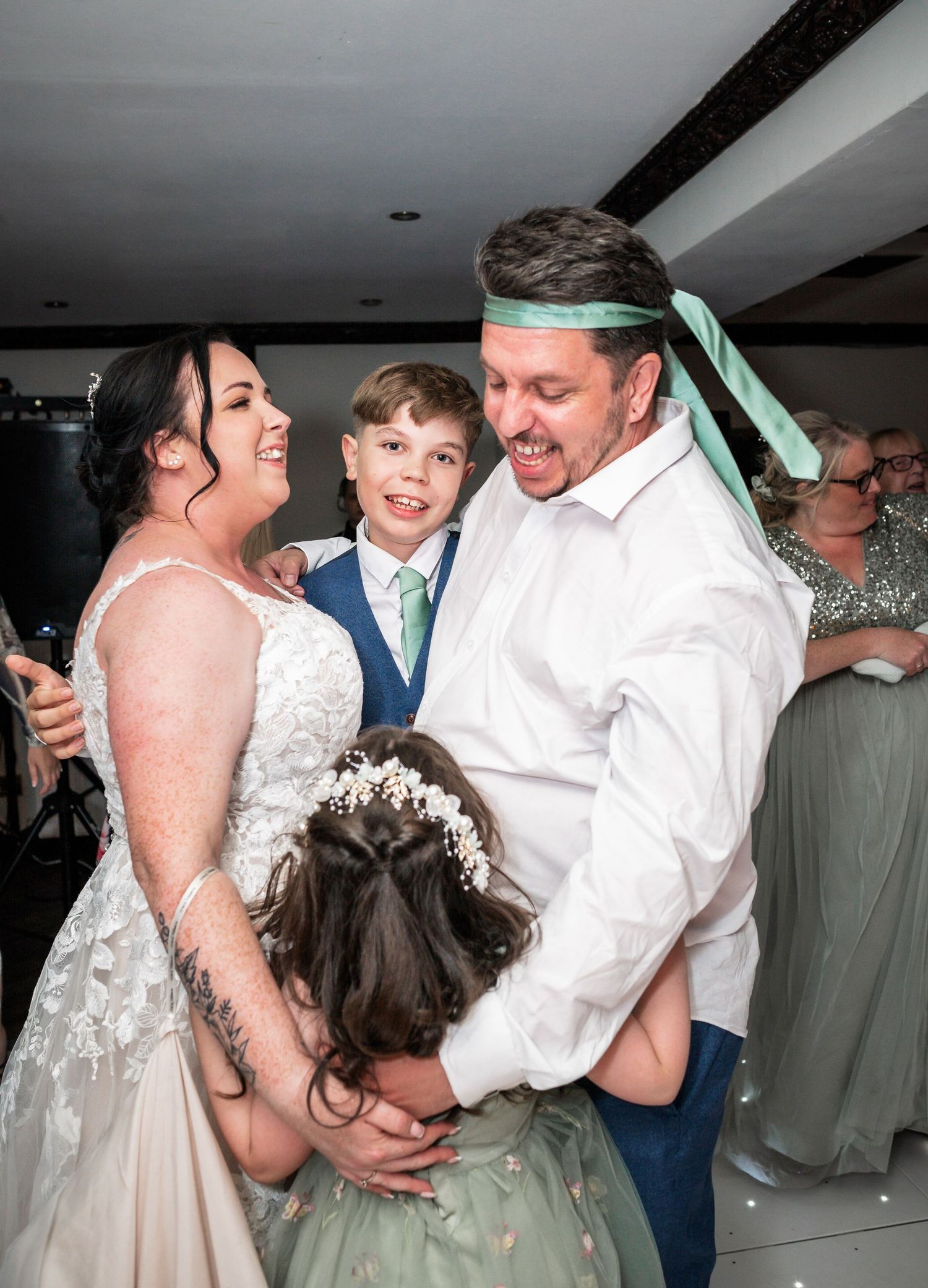 A celebratory dance moment during a wedding reception with guests looking on.