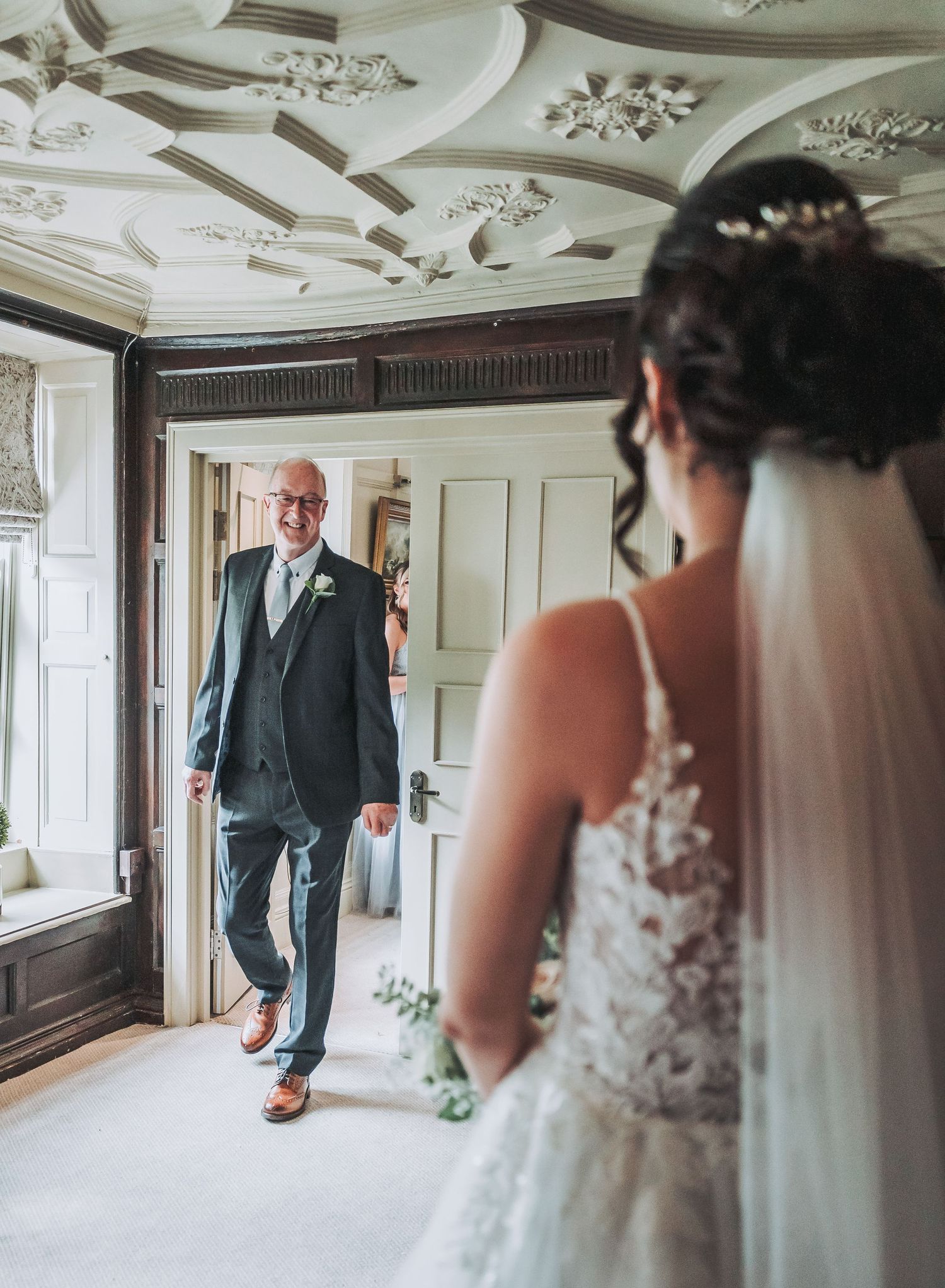 A touching first look moment between a father and bride in an ornately decorated room.