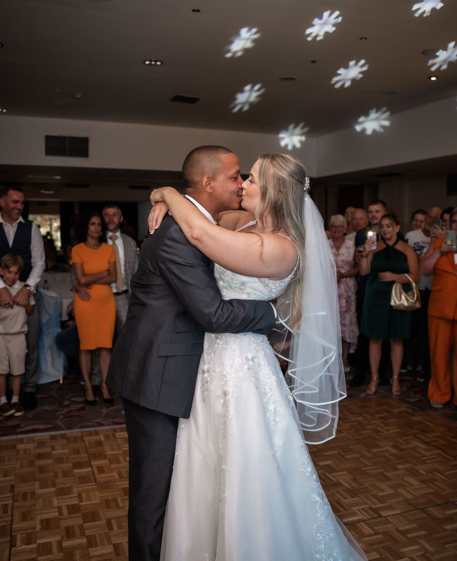 Couple shares their first dance under projected snowflake patterns at their wedding reception.