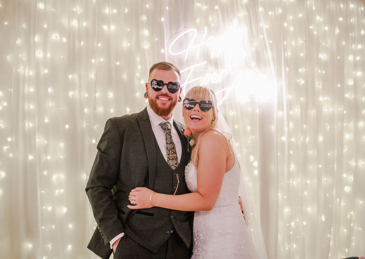 A creative wedding portrait with sparkly backdrop lighting and celebratory masquerade masks.