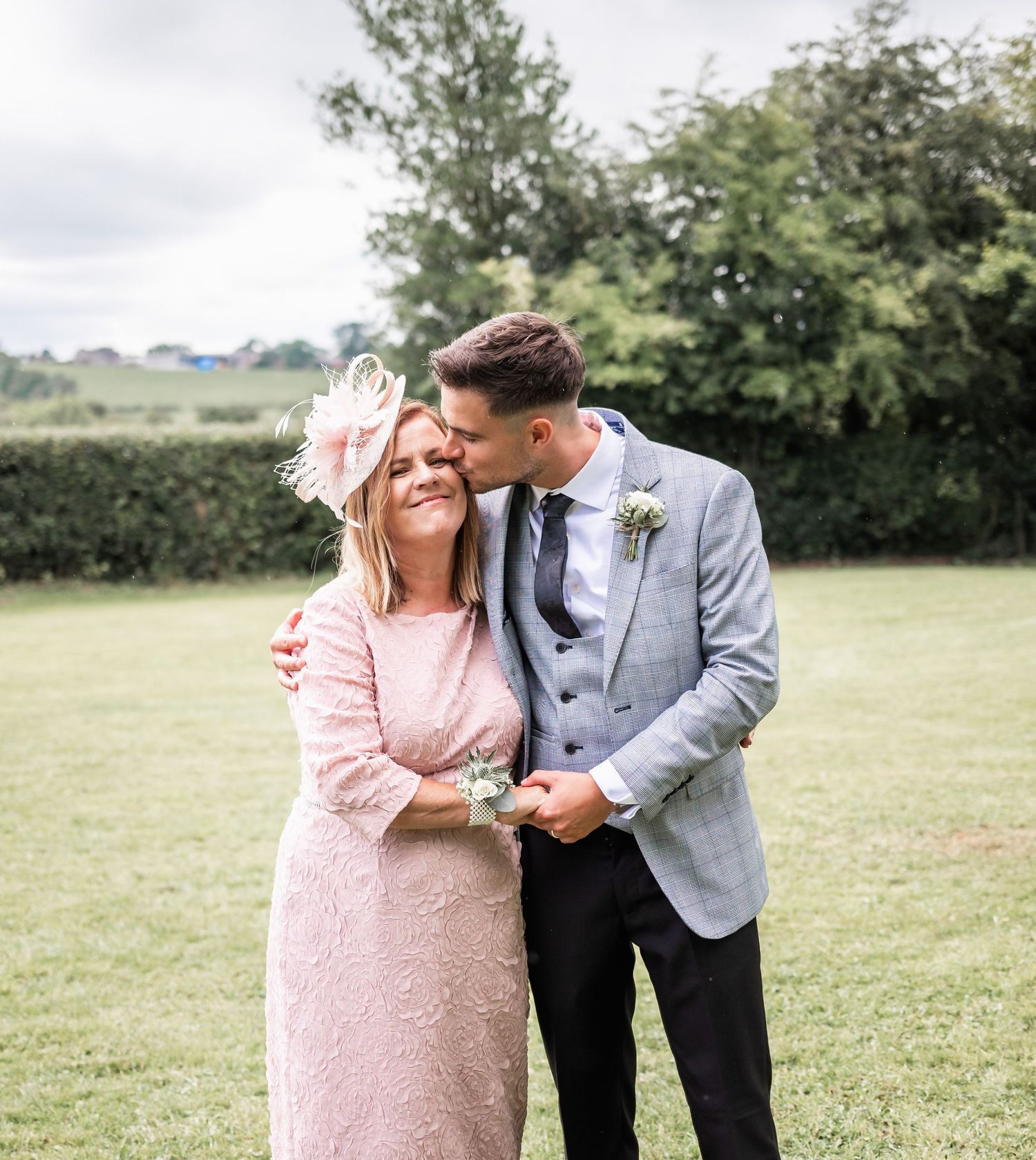 A touching outdoor moment between two people at a formal event in a garden setting.