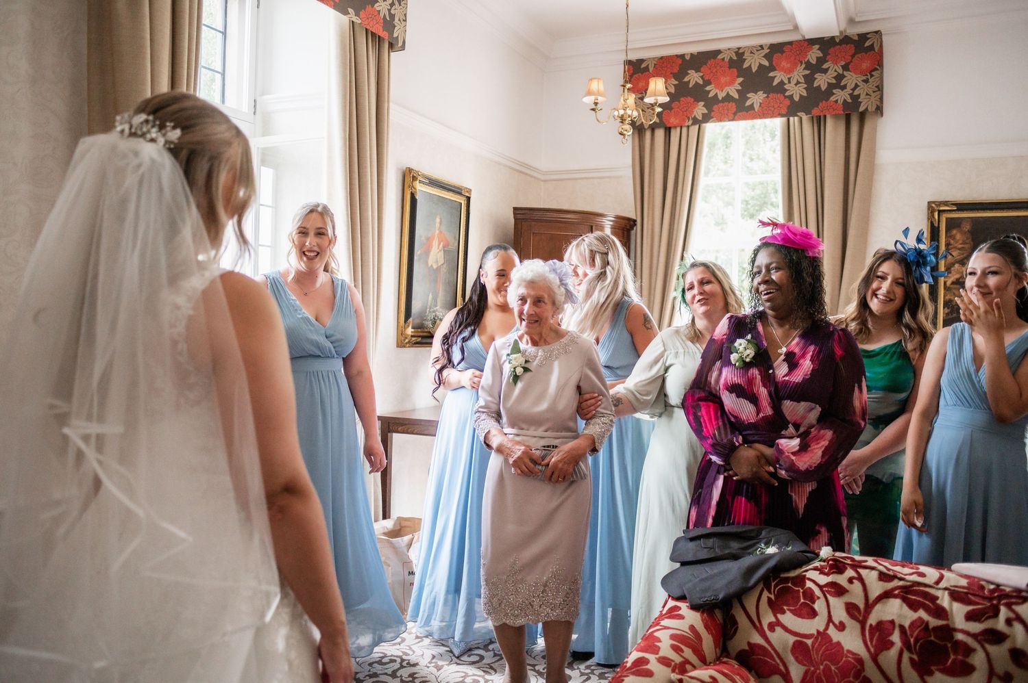 A heartwarming pre-wedding moment shows attendees in blue dresses sharing emotional reactions in an elegant indoor setting.