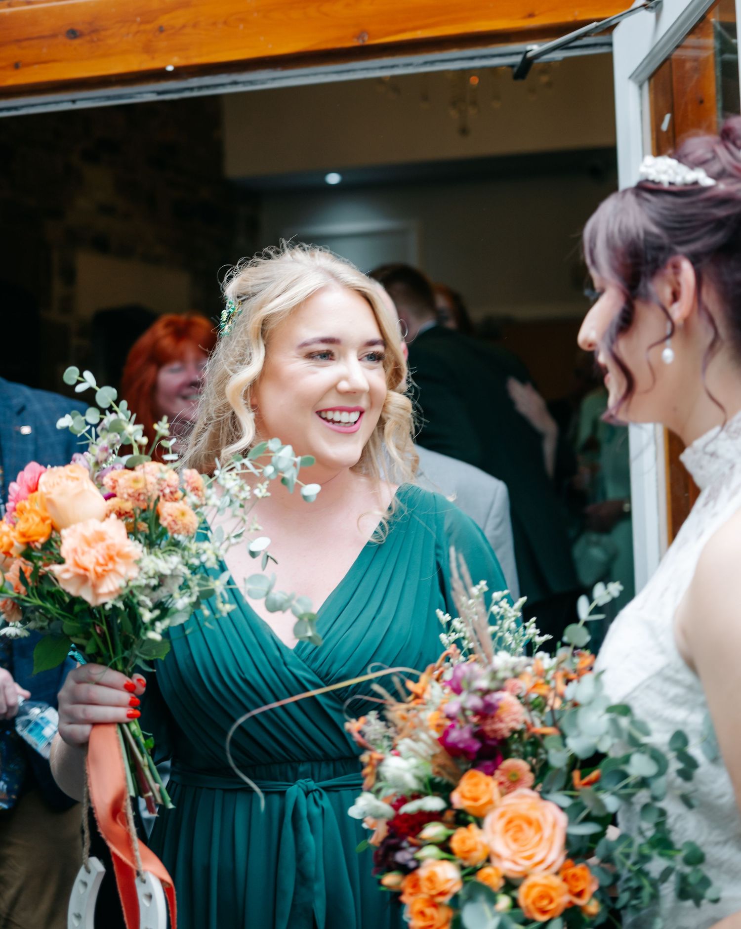 Joyful wedding moment with bridesmaids holding vibrant autumn bouquets.