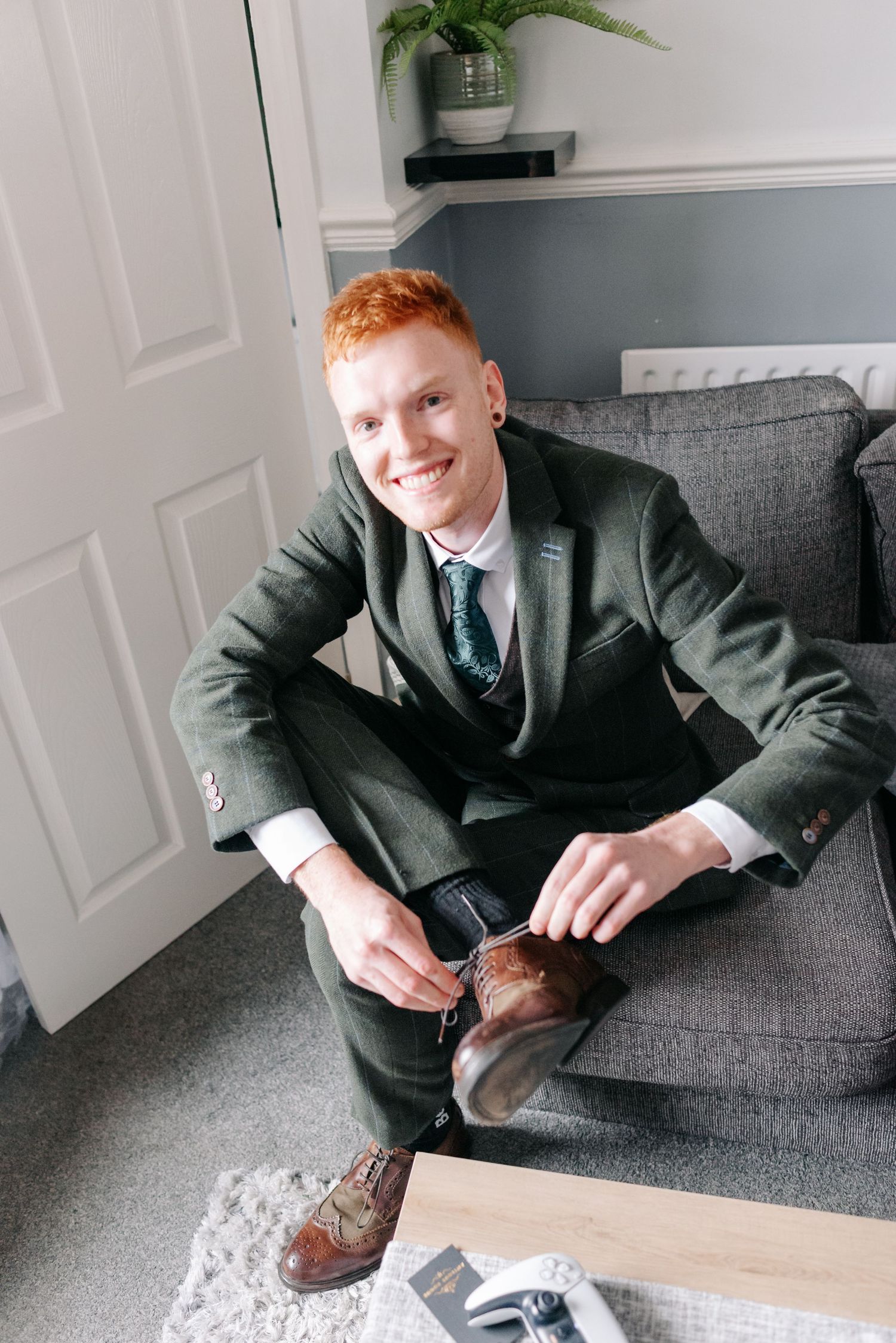 Person in dark suit lounges on gray couch in modern interior setting.
